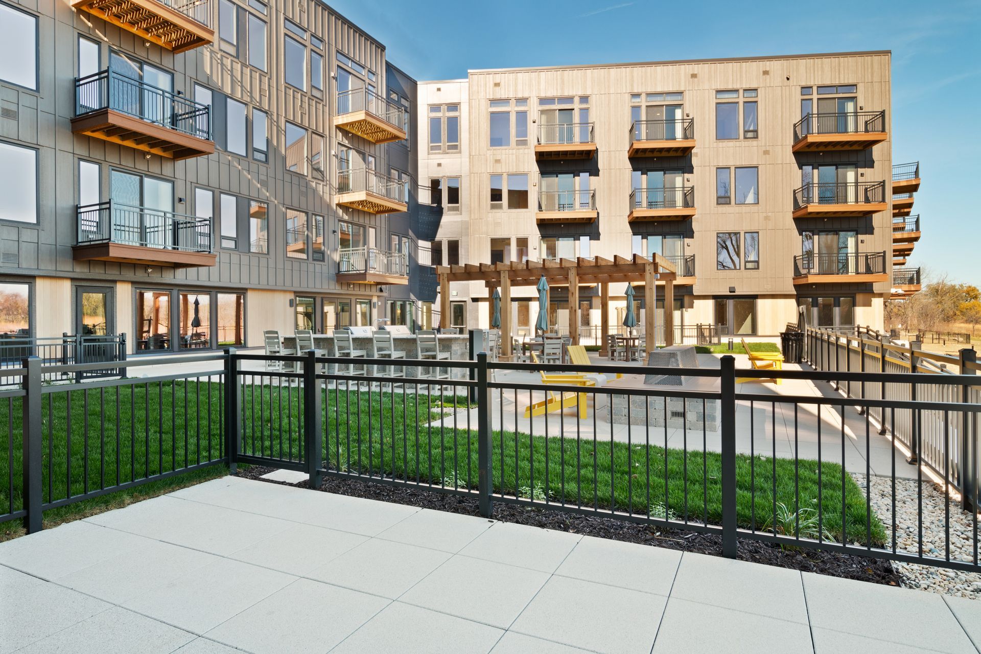 Large patio with a fence and view of community terrace.