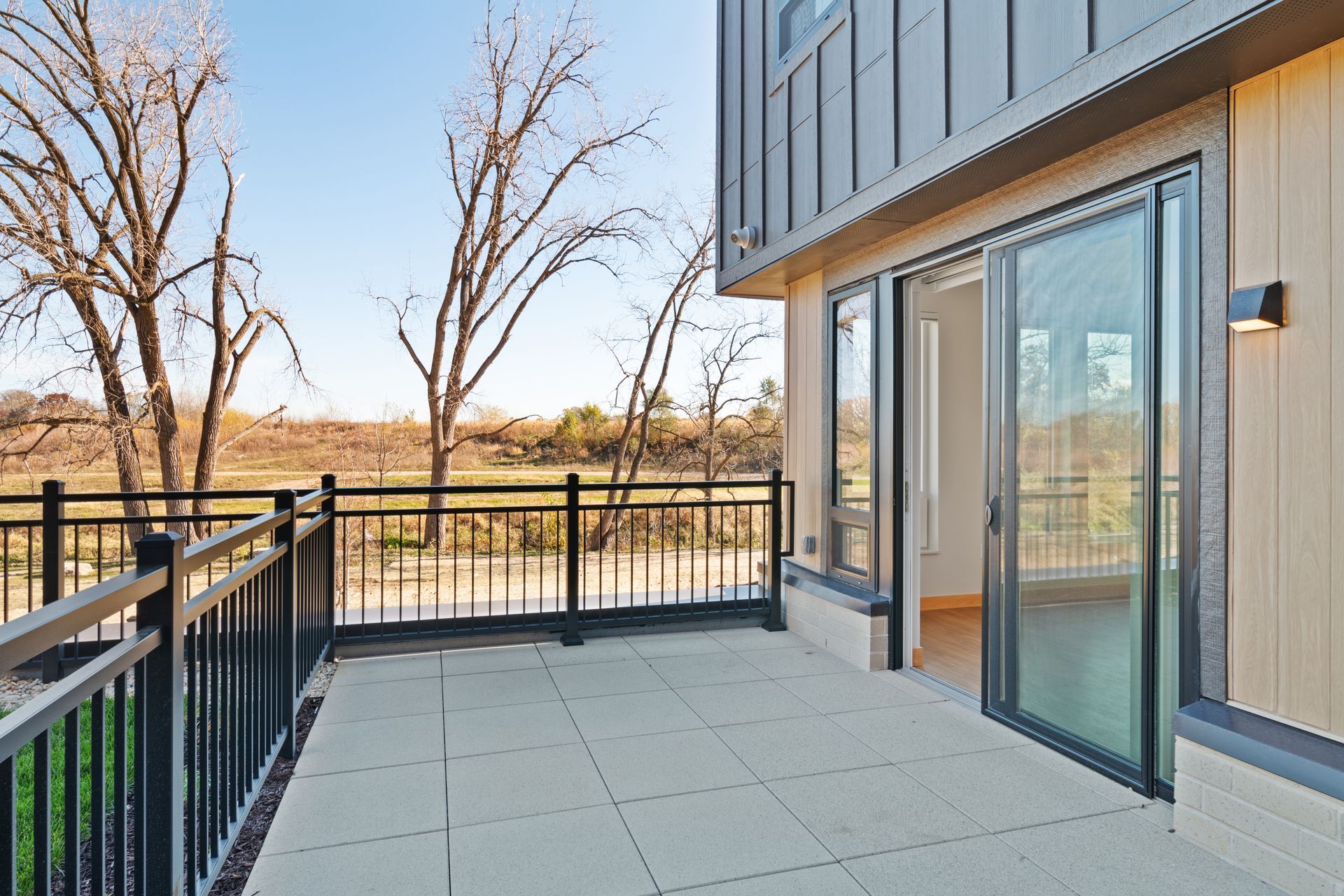 Large patio with a railing and sliding glass doors leading into apartment.