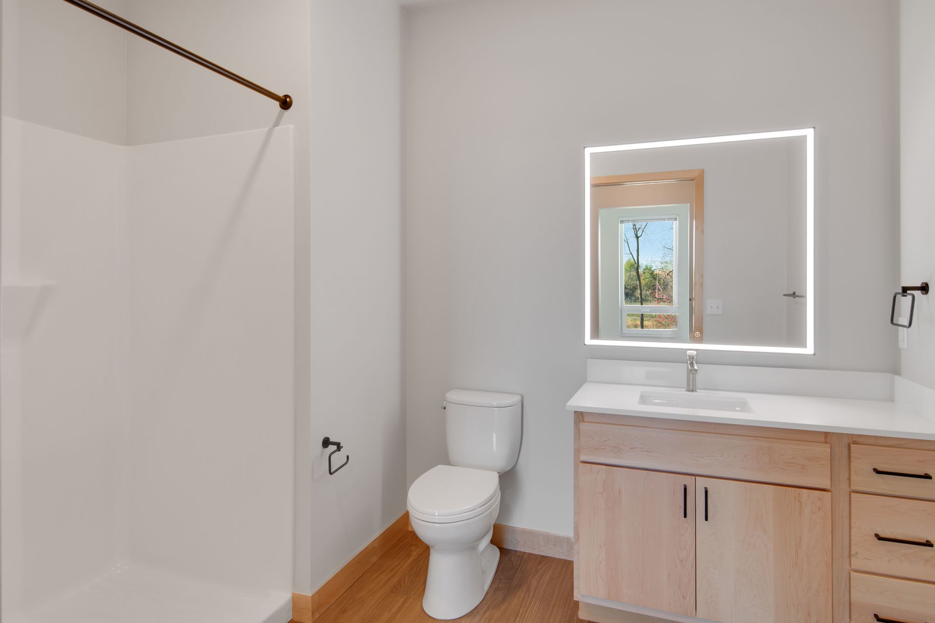 A bathroom with a toilet , sink , mirror and shower.