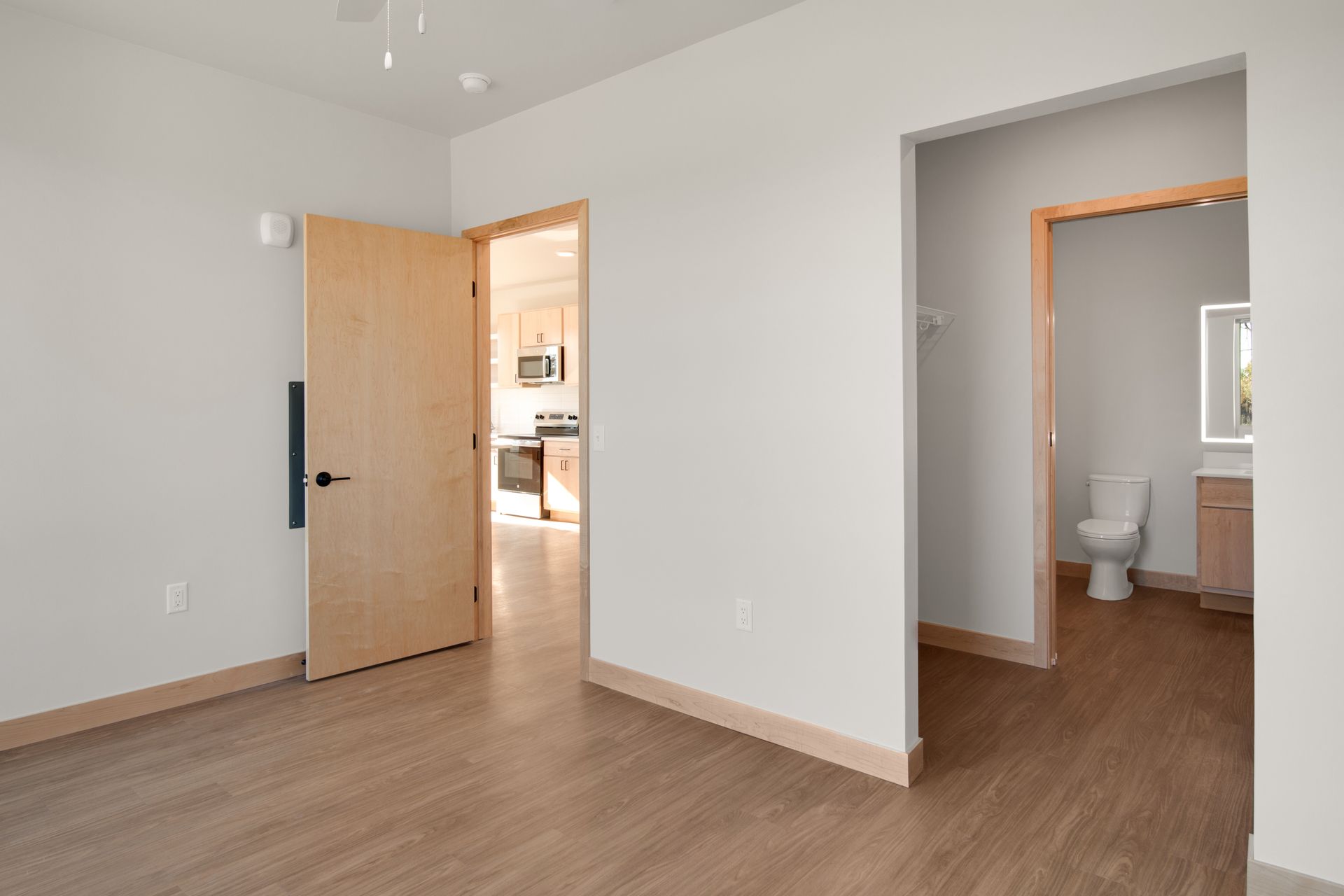 An empty room with wooden floors and a toilet.