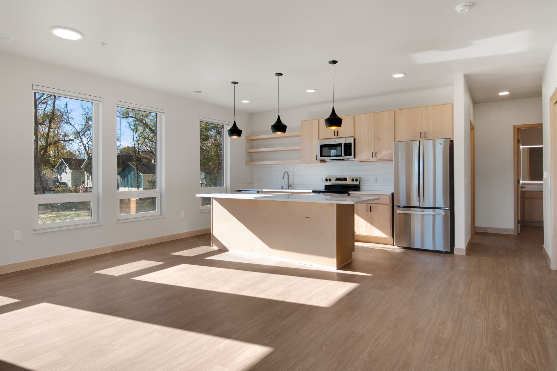 An empty kitchen with stainless steel appliances and wooden cabinets.