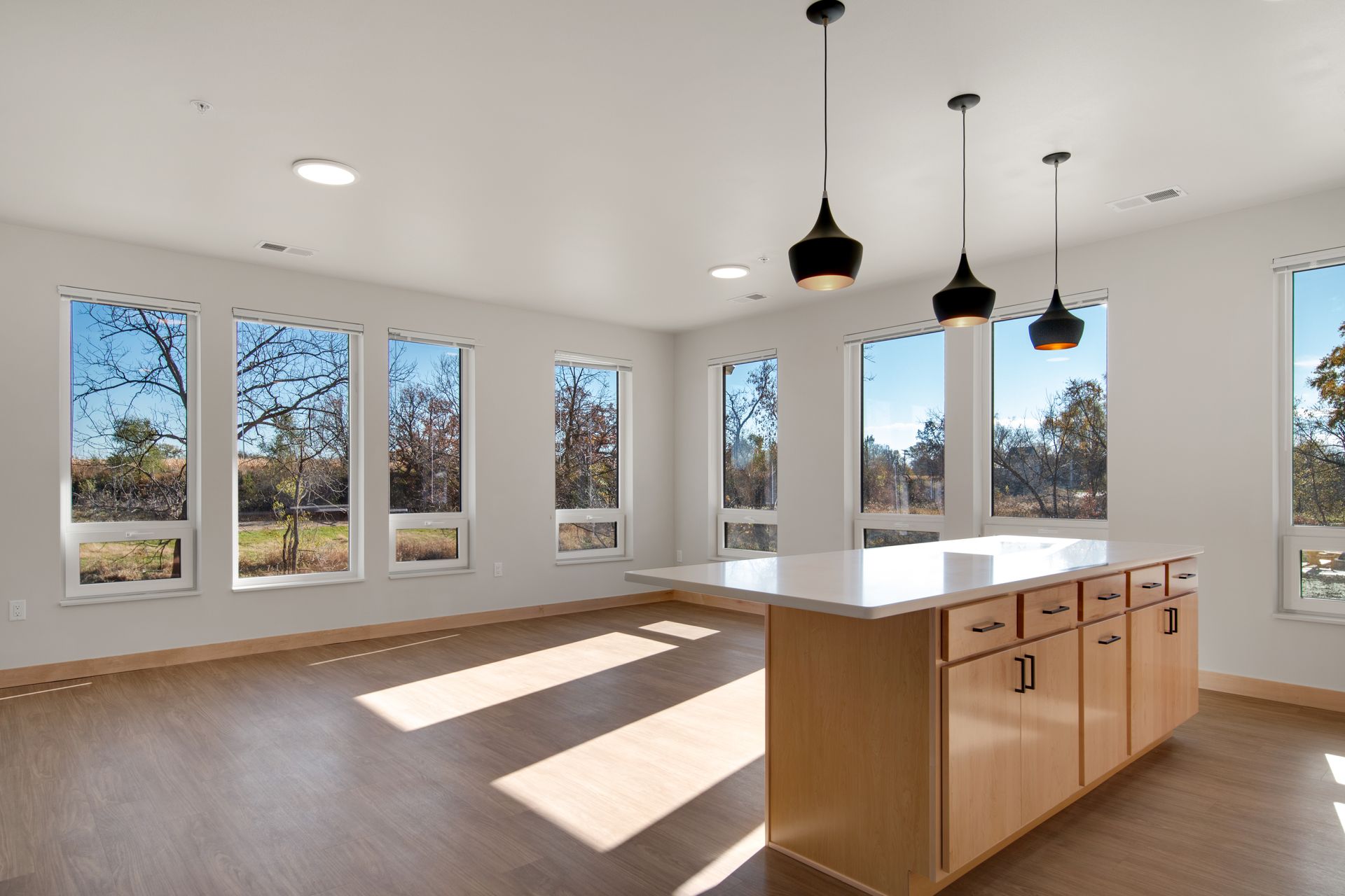 An empty kitchen with a large island and lots of windows.