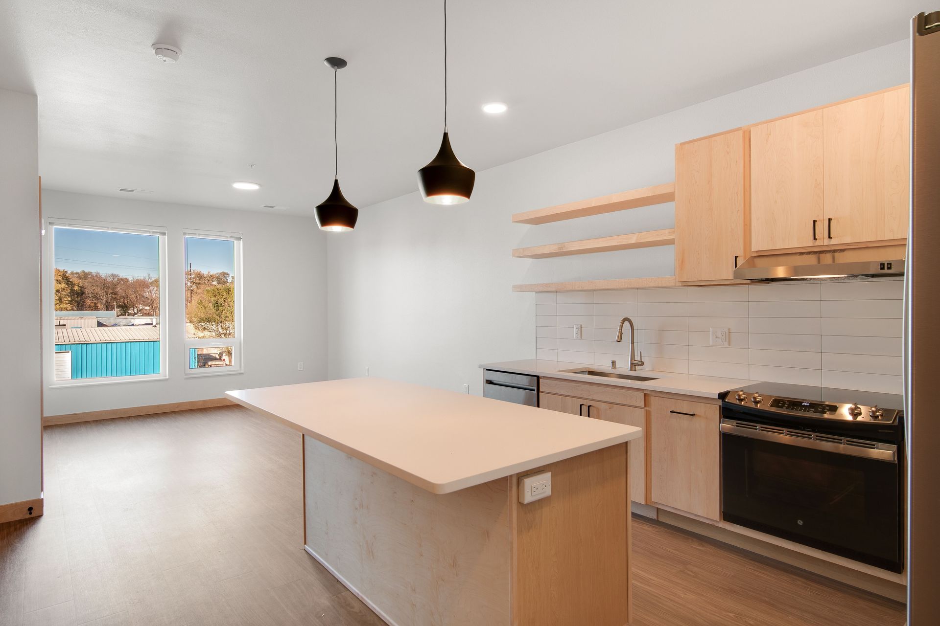 An empty kitchen with a large island in the middle of the room.
