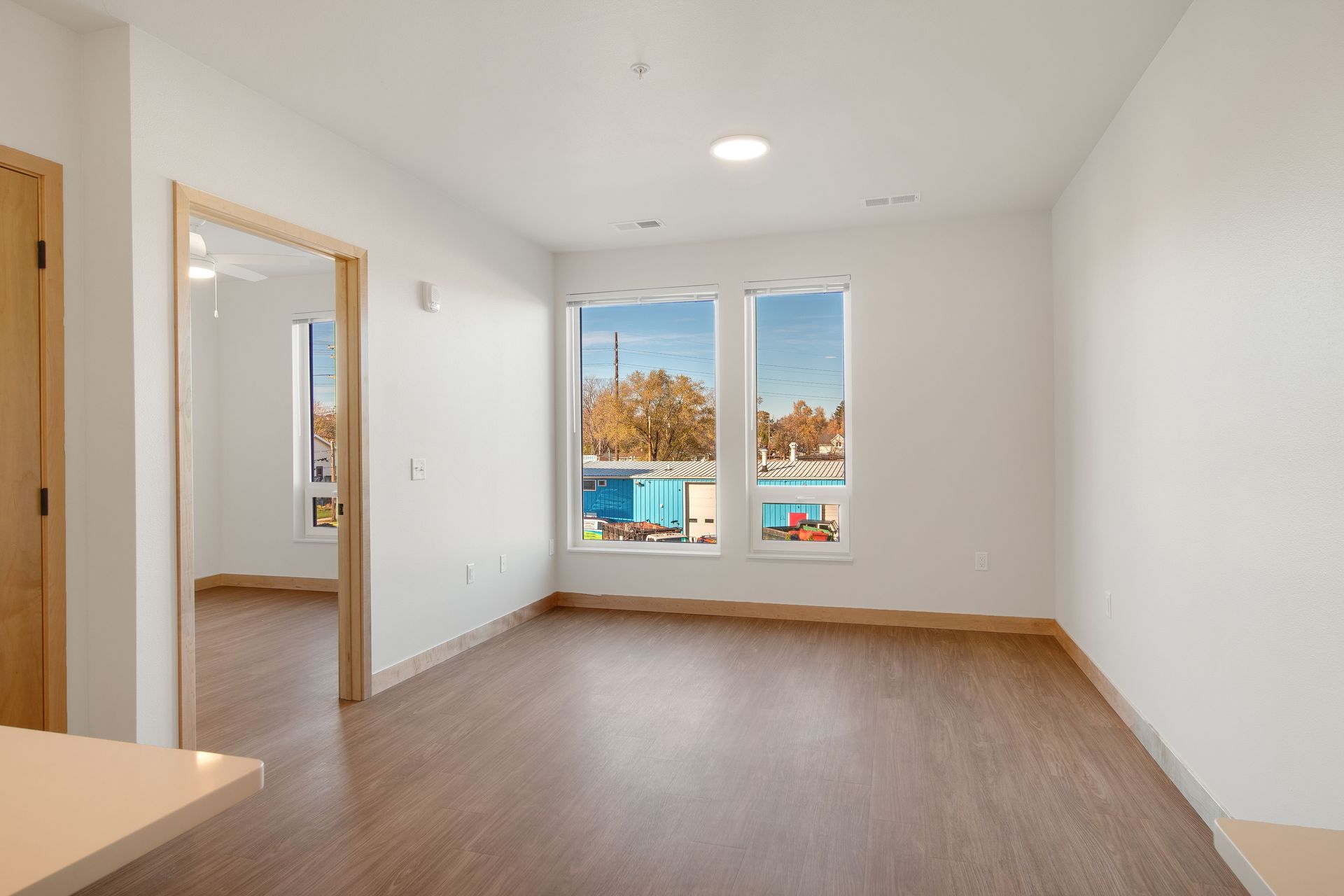 An empty living room with hardwood floors and two windows.