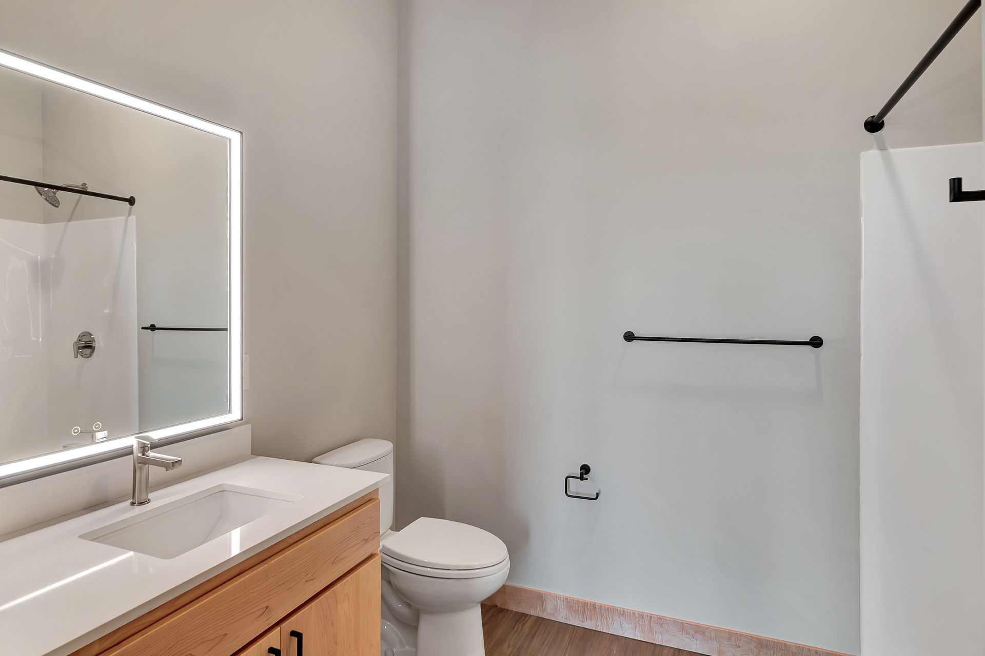 A bathroom with a toilet , sink , mirror and shower.
