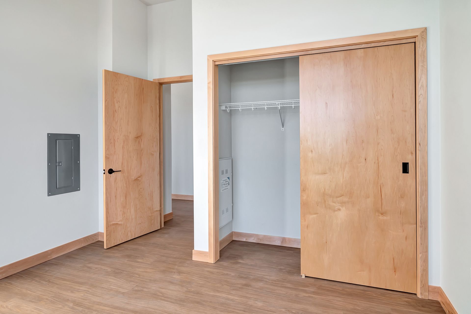 An empty bedroom with wooden doors and a closet.
