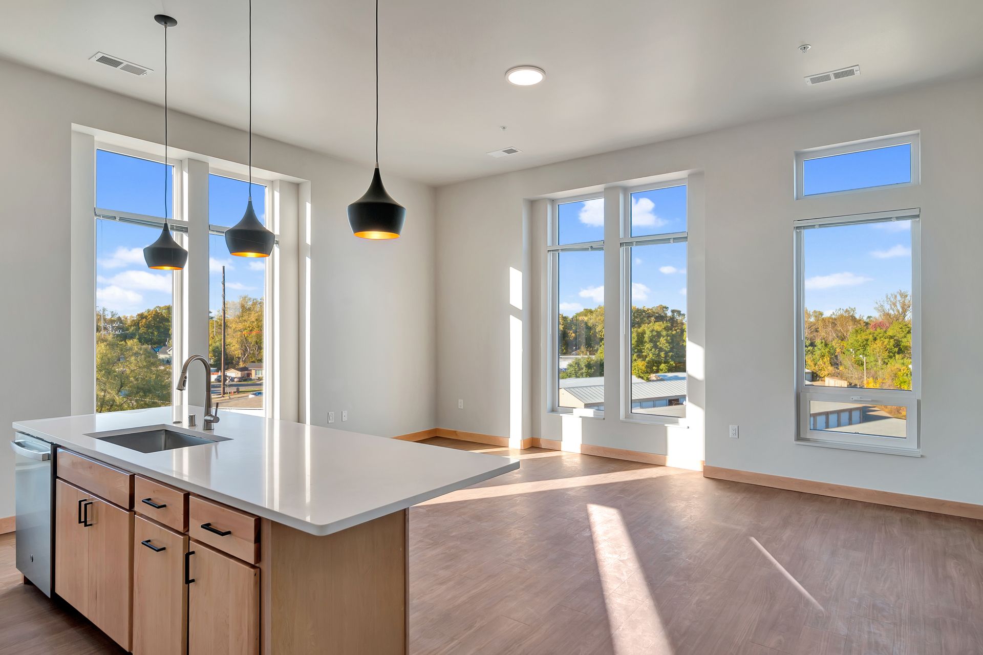 An empty kitchen with a large island and lots of windows.