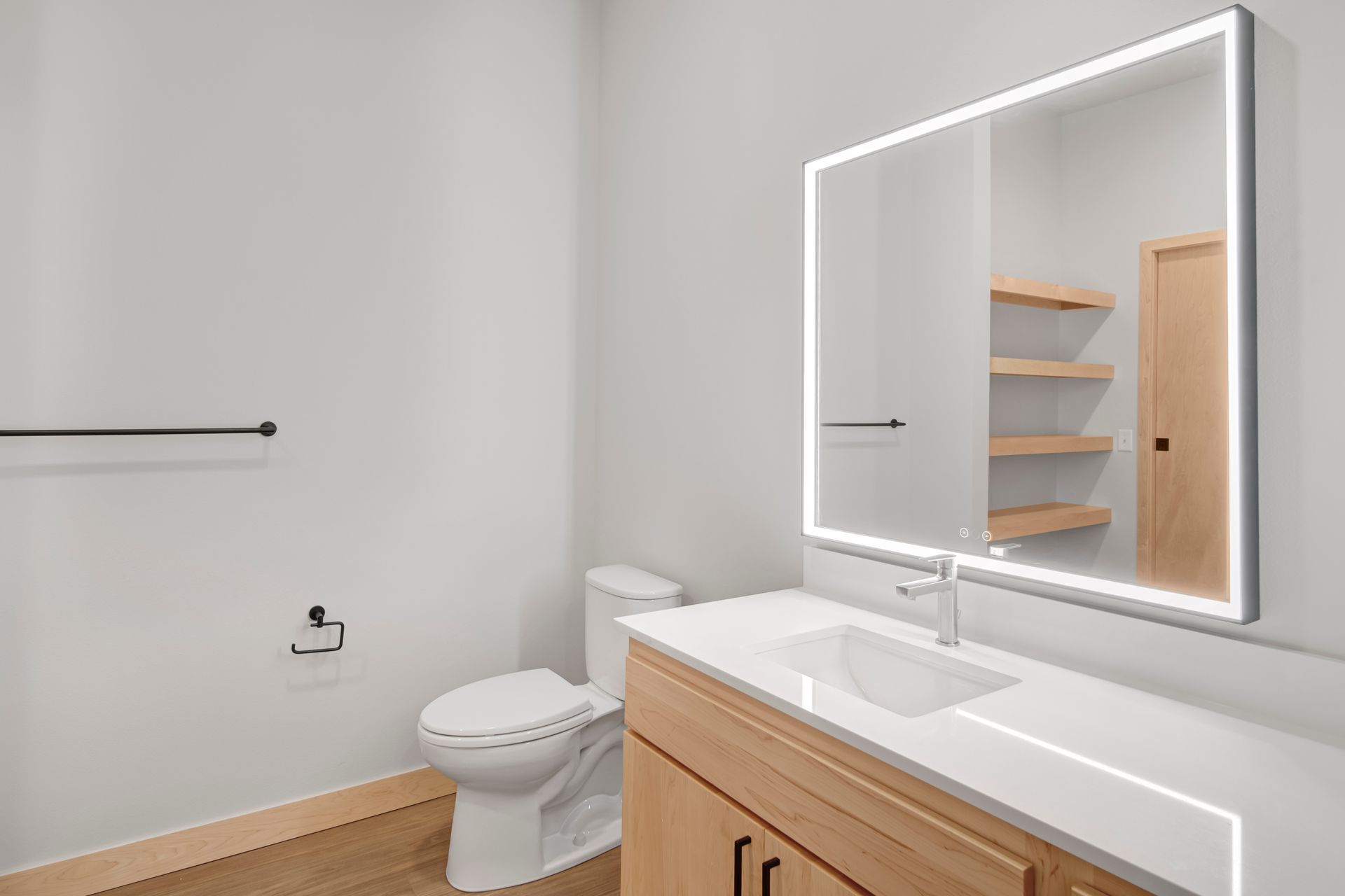 A bathroom with a toilet , sink and mirror.