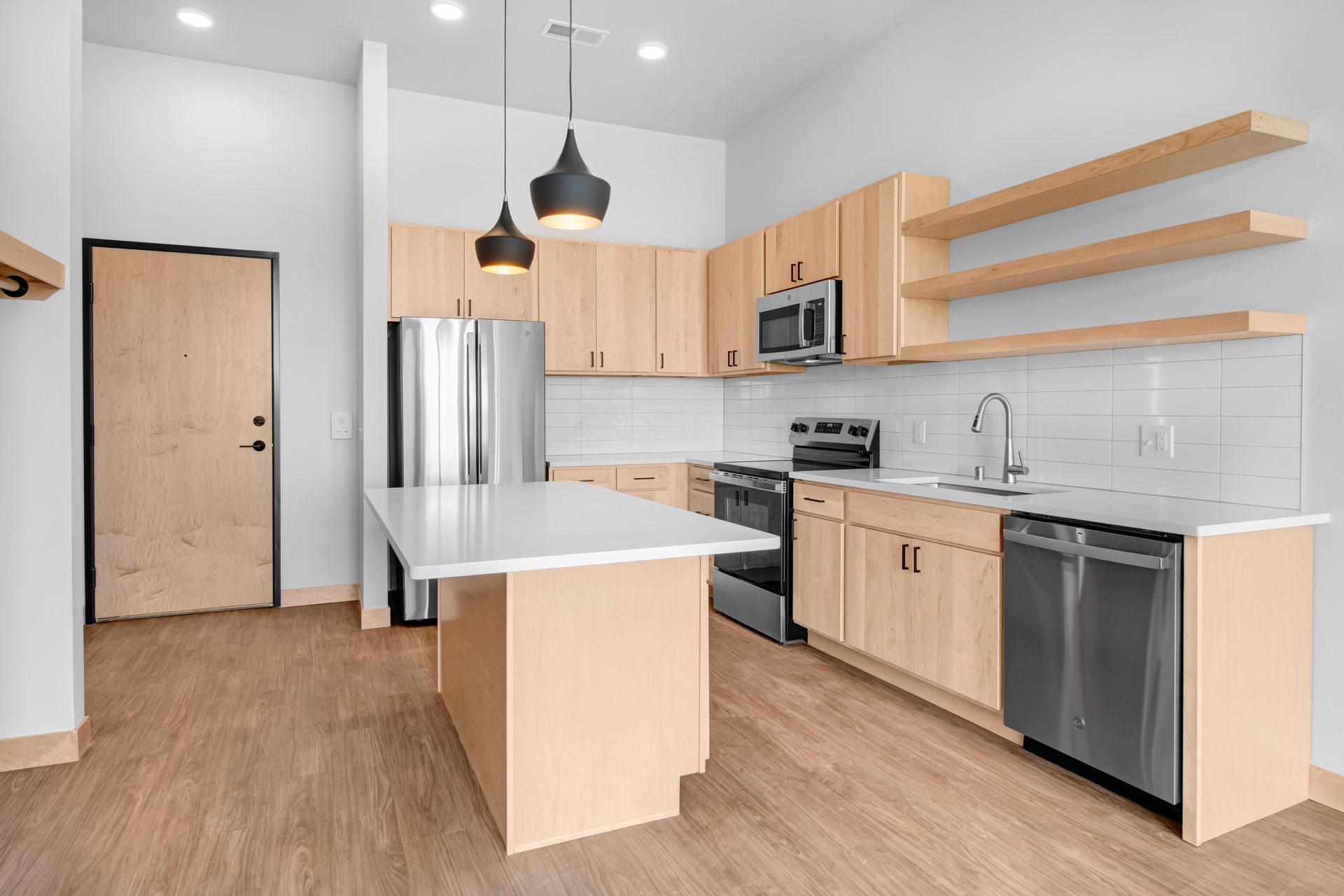 A kitchen with wooden cabinets , stainless steel appliances , and a large island.