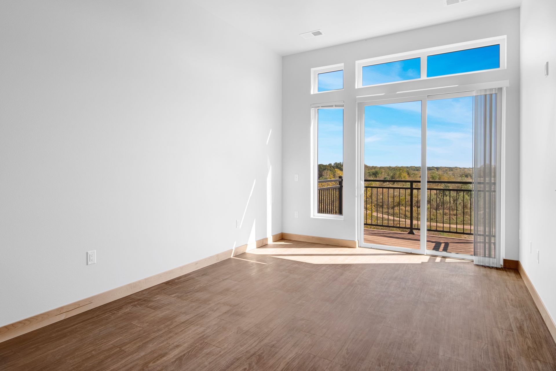 An empty room with a balcony and sliding glass doors.