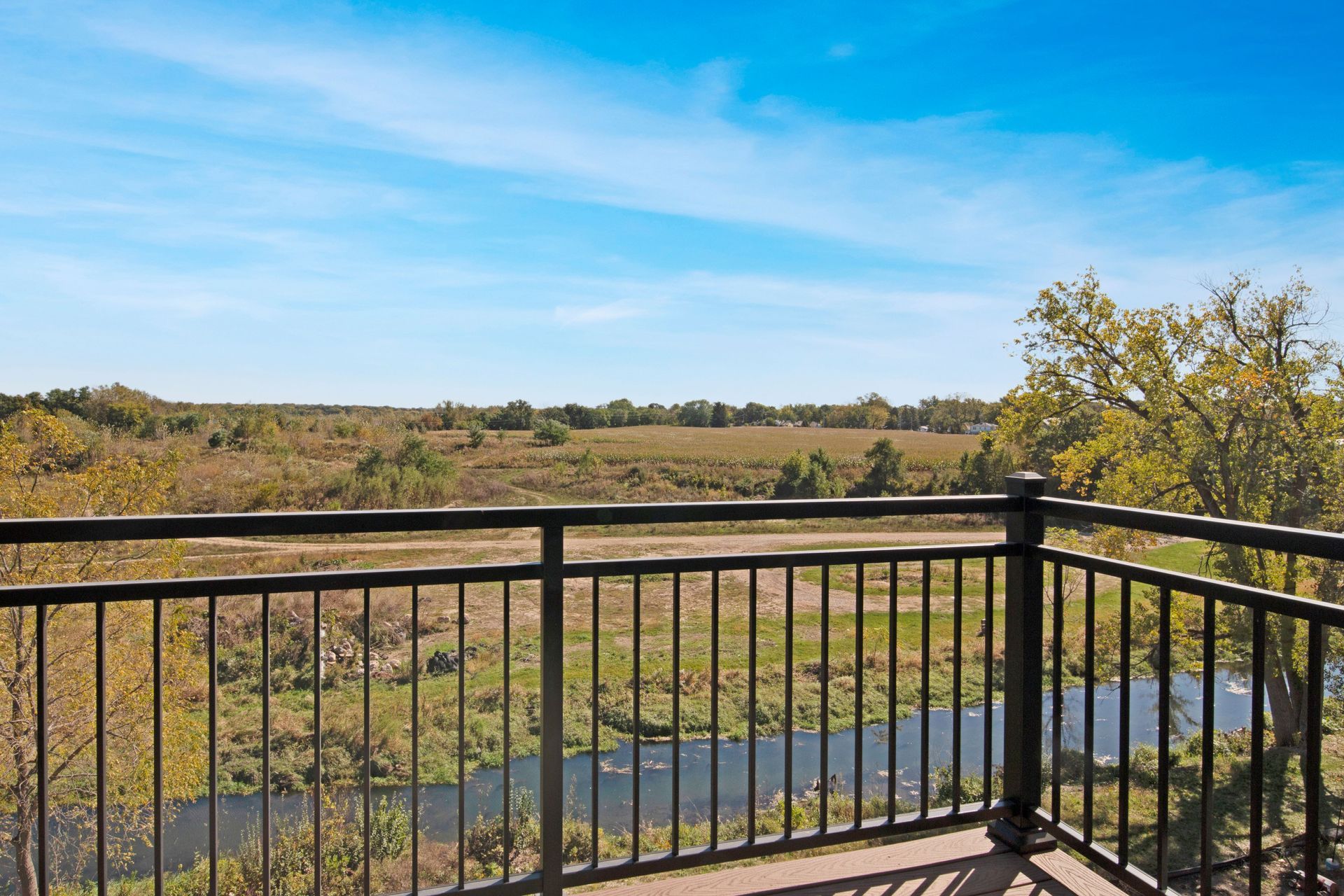 A balcony with a view of a river and a field.