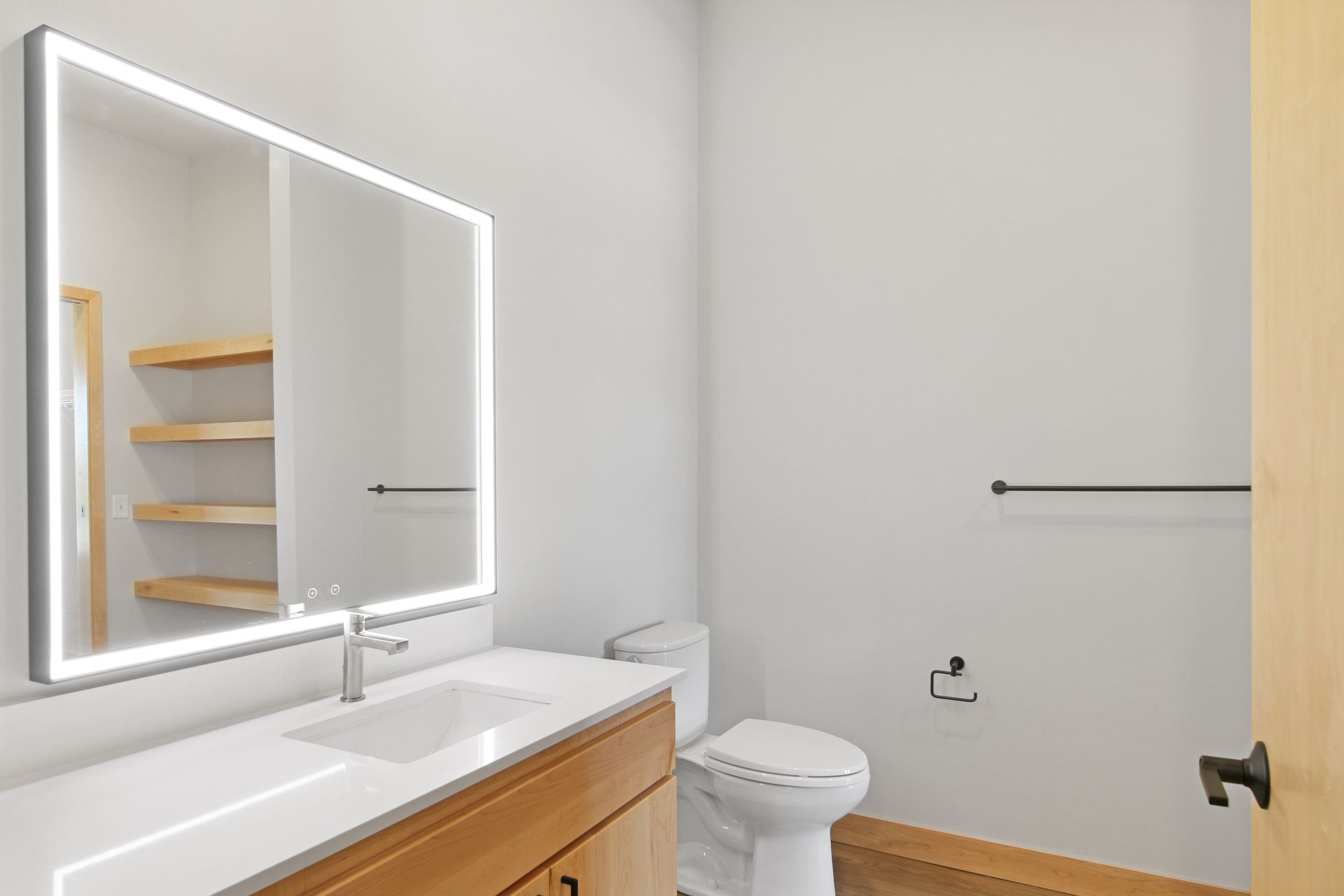 A bathroom with a toilet , sink and mirror.