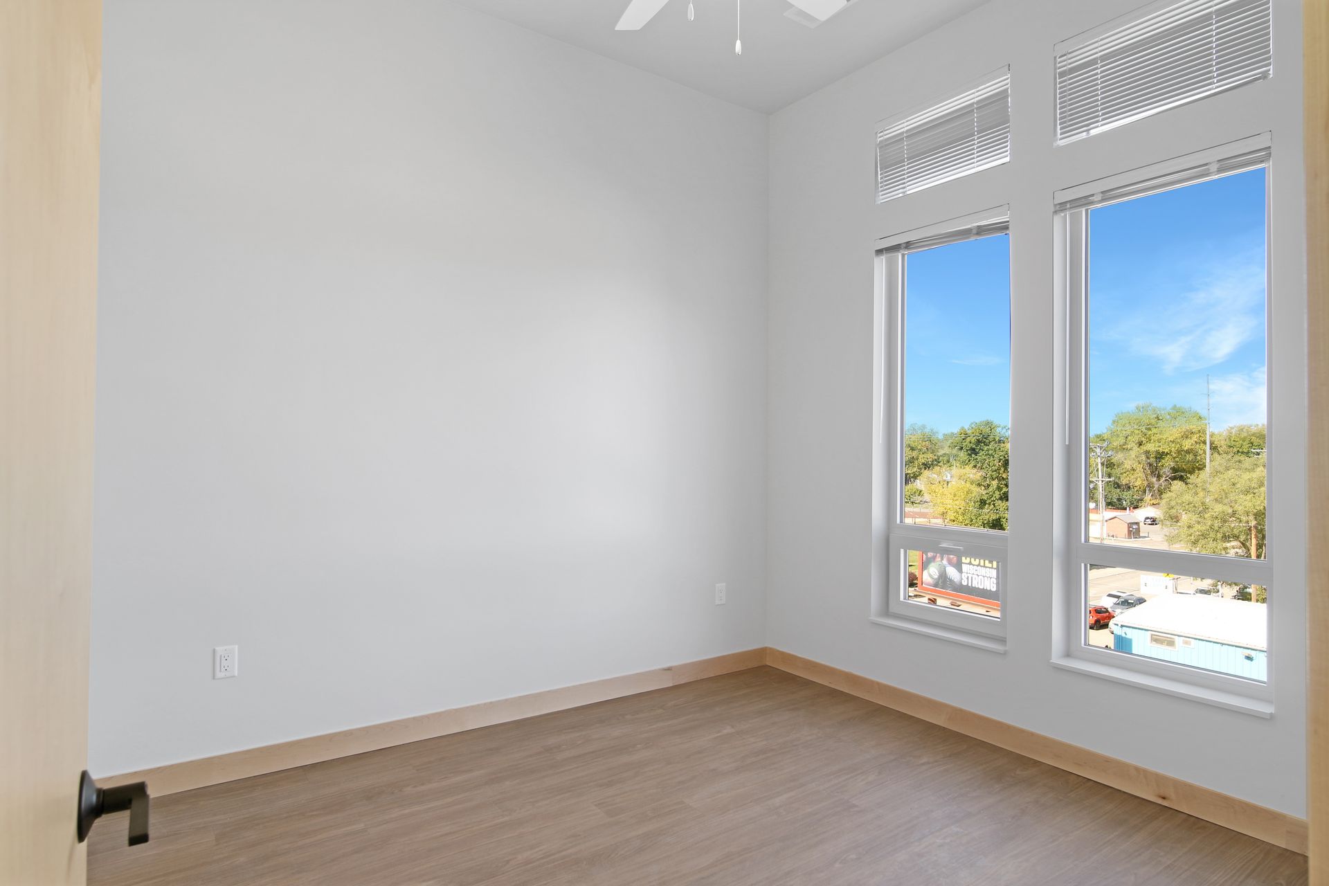 An empty room with two windows and a ceiling fan.