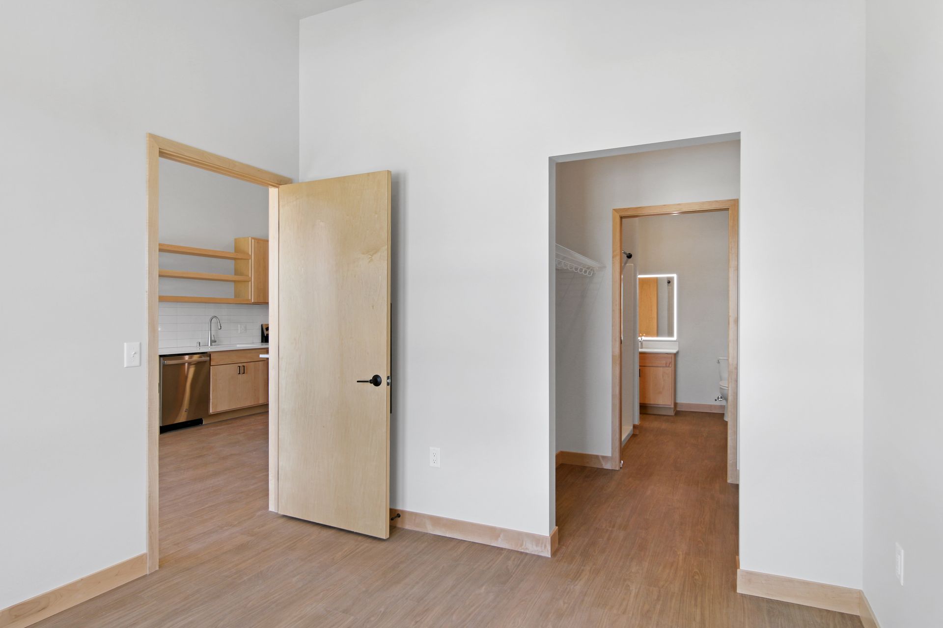 An empty apartment with a kitchen , closet , and bathroom.