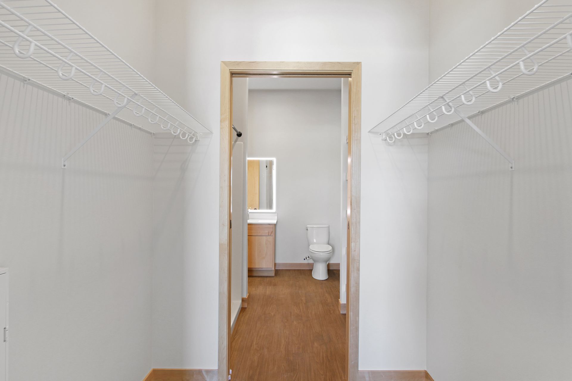 A walk in closet with a toilet , sink and mirror.