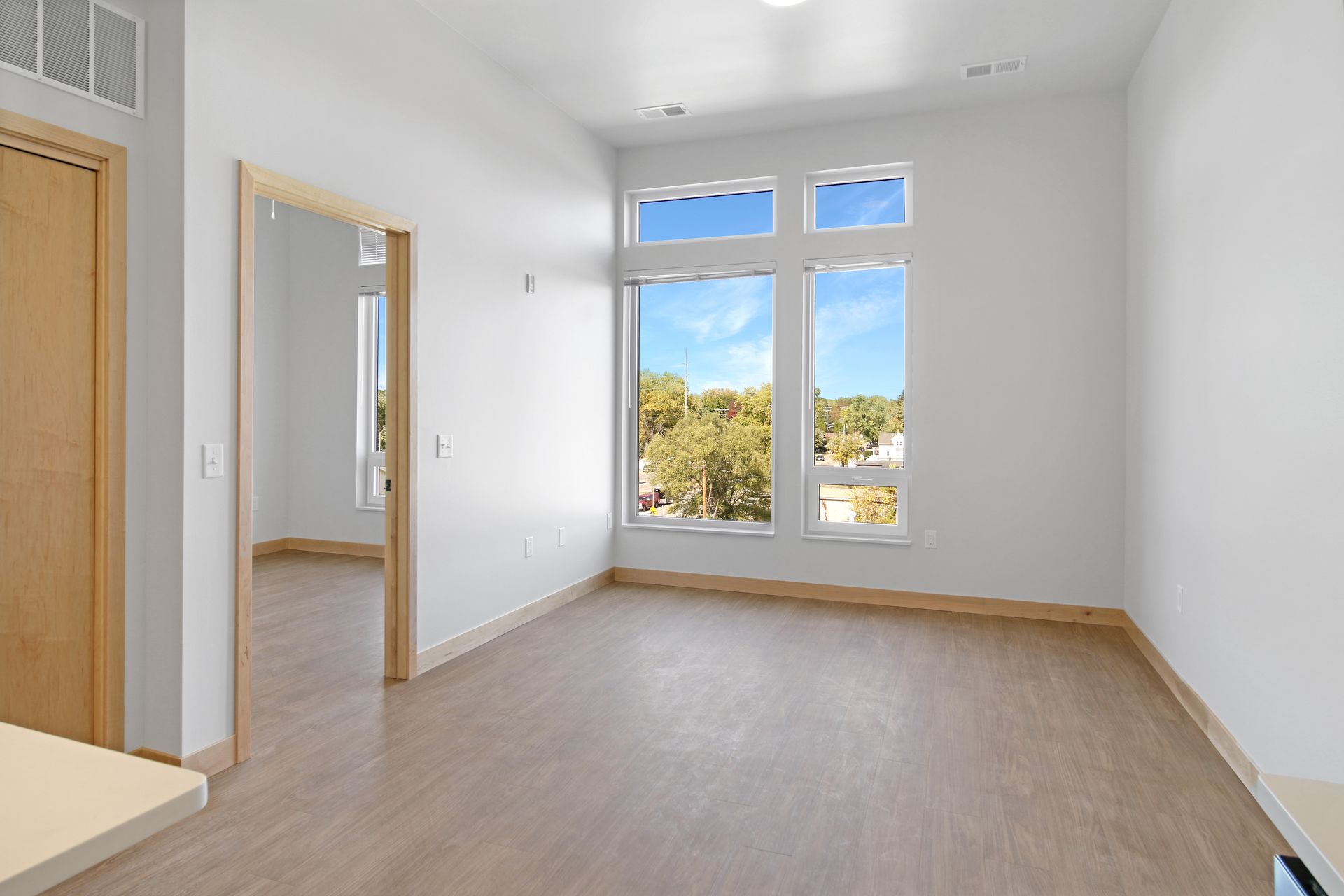 An empty living room with a lot of windows and a wooden floor.