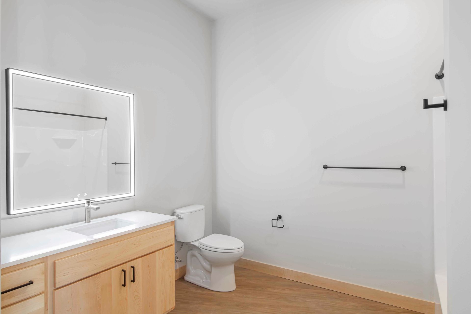 A bathroom with a toilet , sink , mirror and shower.