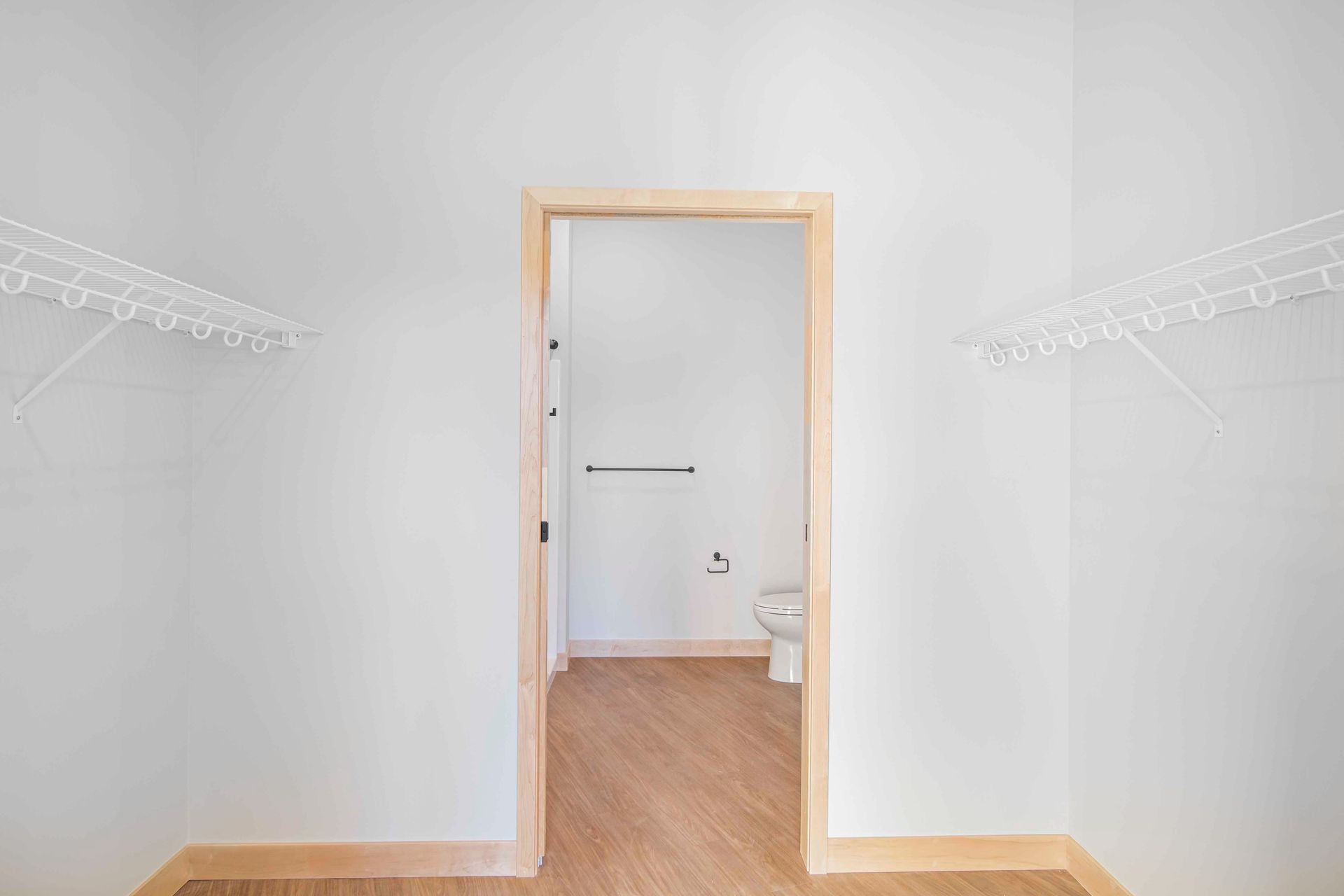An empty walk in closet with a door leading to a bathroom.