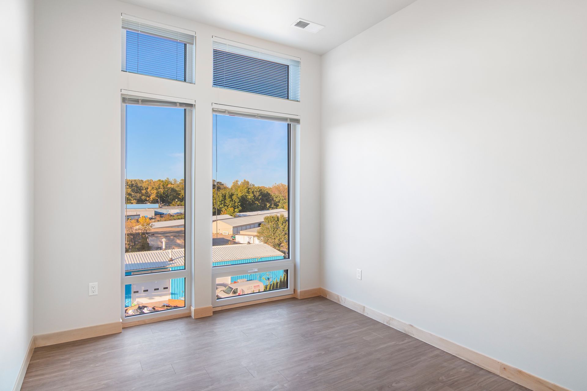 An empty room with a large window and a view of a city.