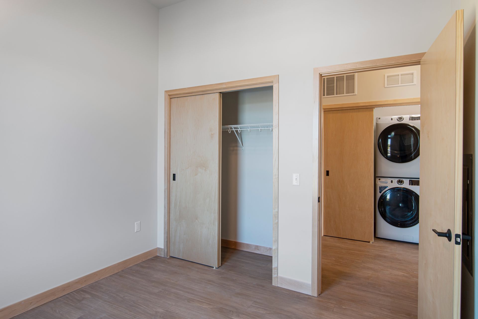 A bedroom with a washer and dryer stacked on top of each other.