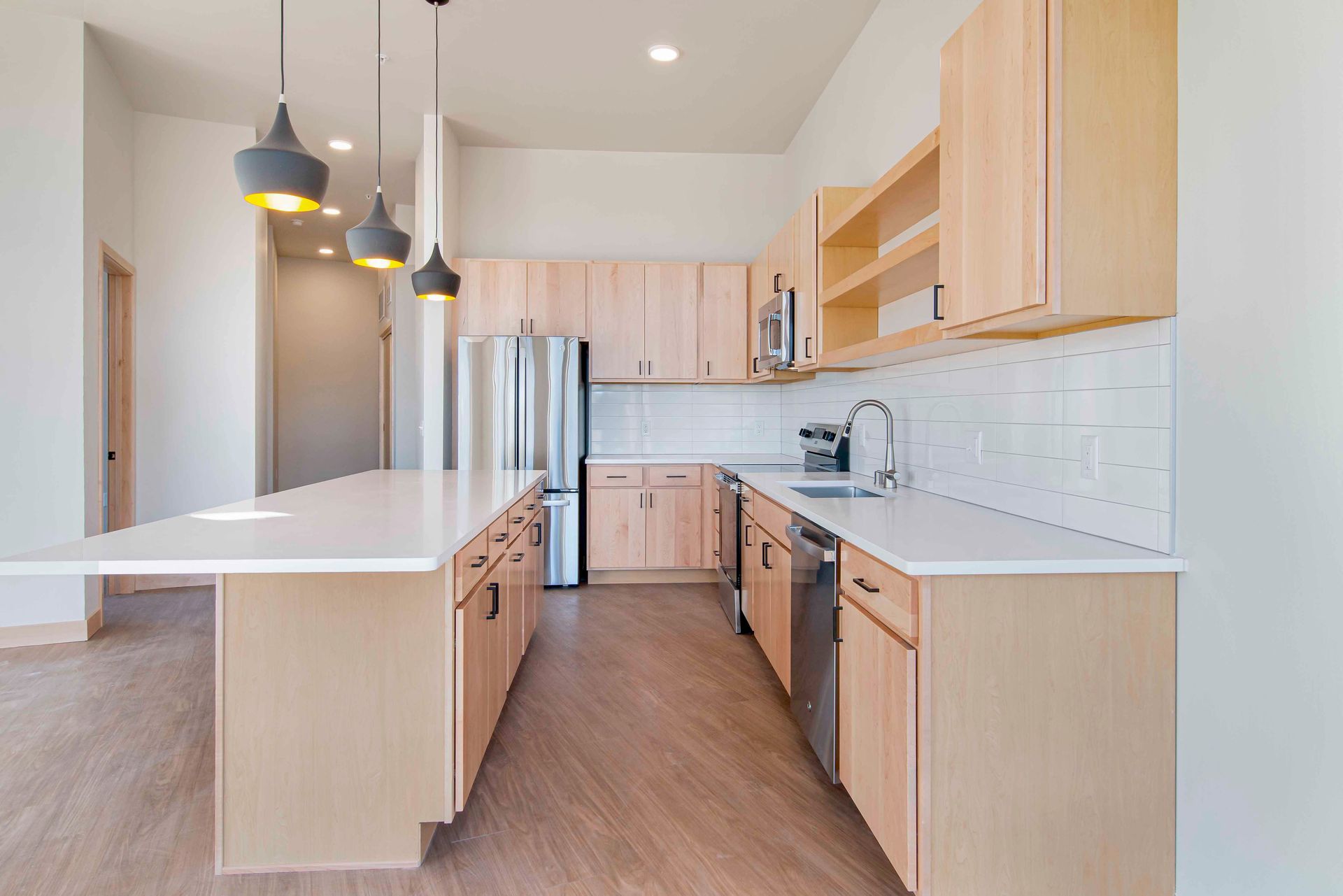 An empty kitchen with wooden cabinets and stainless steel appliances.