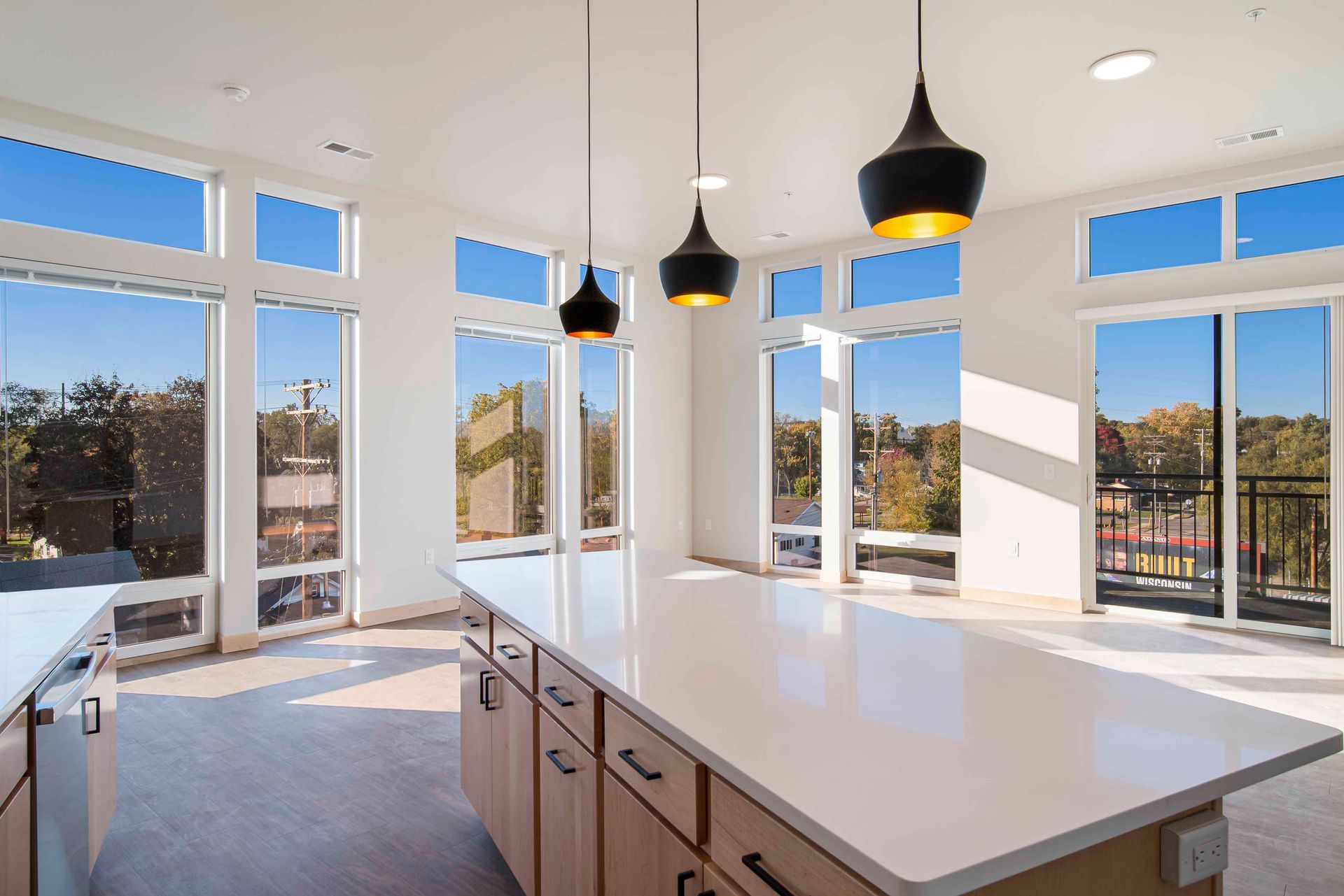 An empty kitchen with a large island and lots of windows.