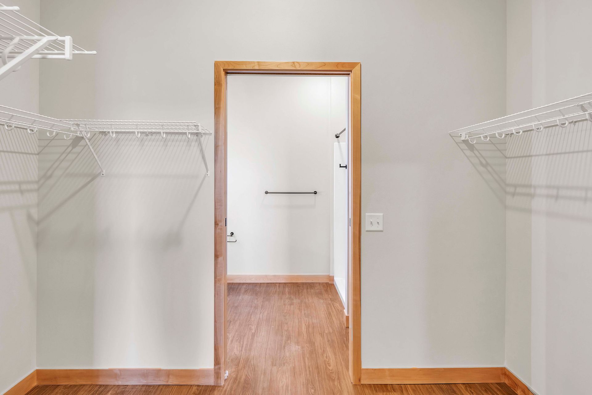 A walk in closet with lots of shelves and a door leading to a bathroom.