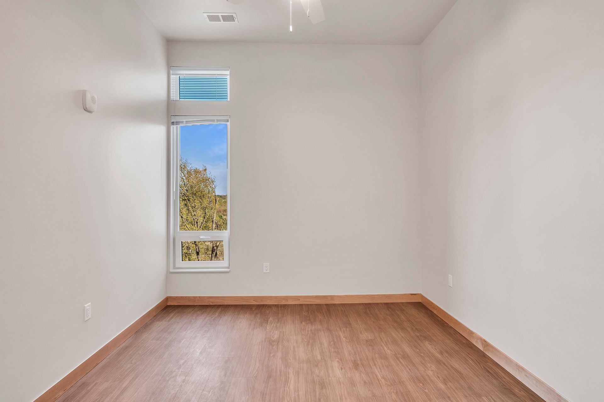 An empty room with a window and wooden floors.