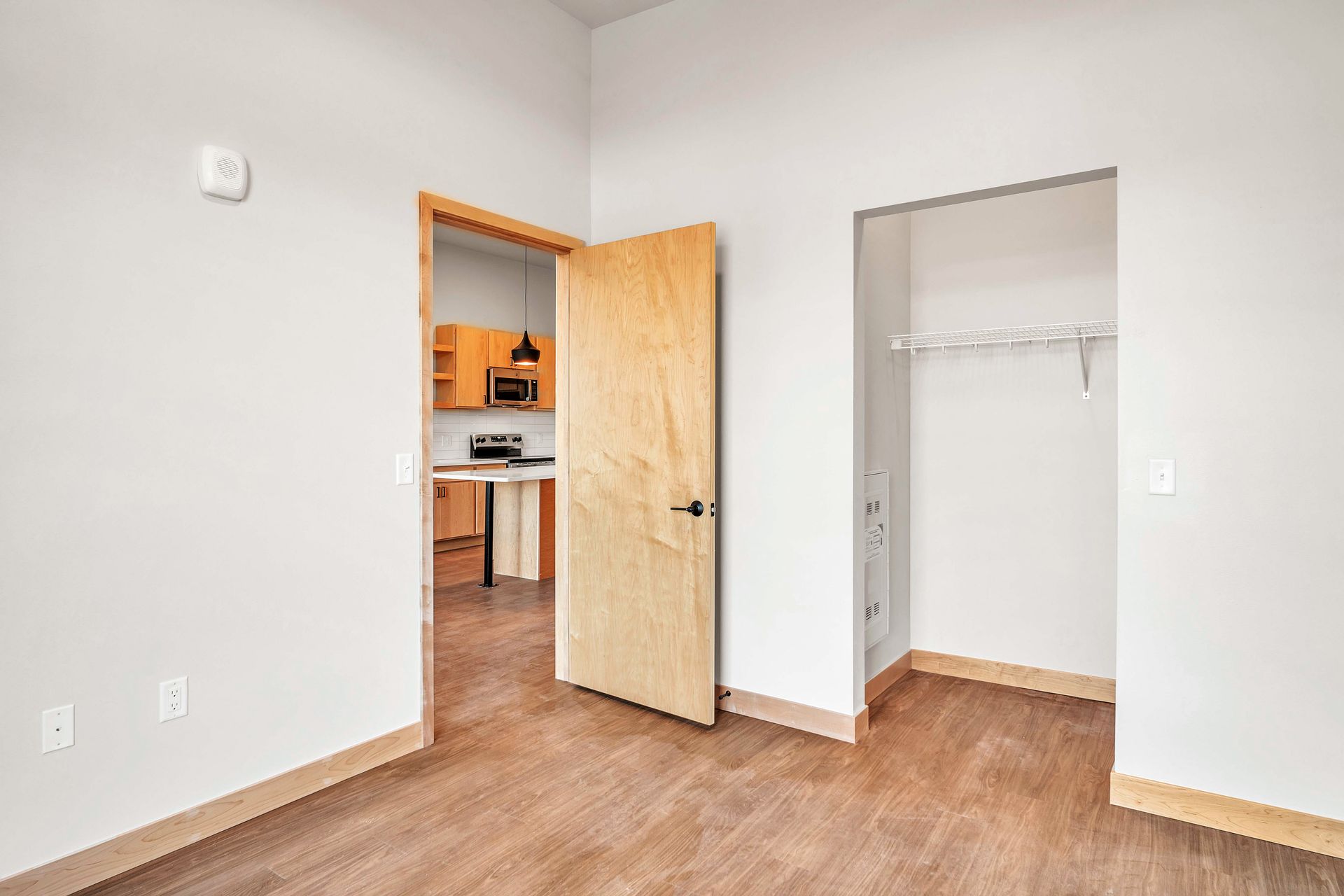 An empty room with hardwood floors and a closet.