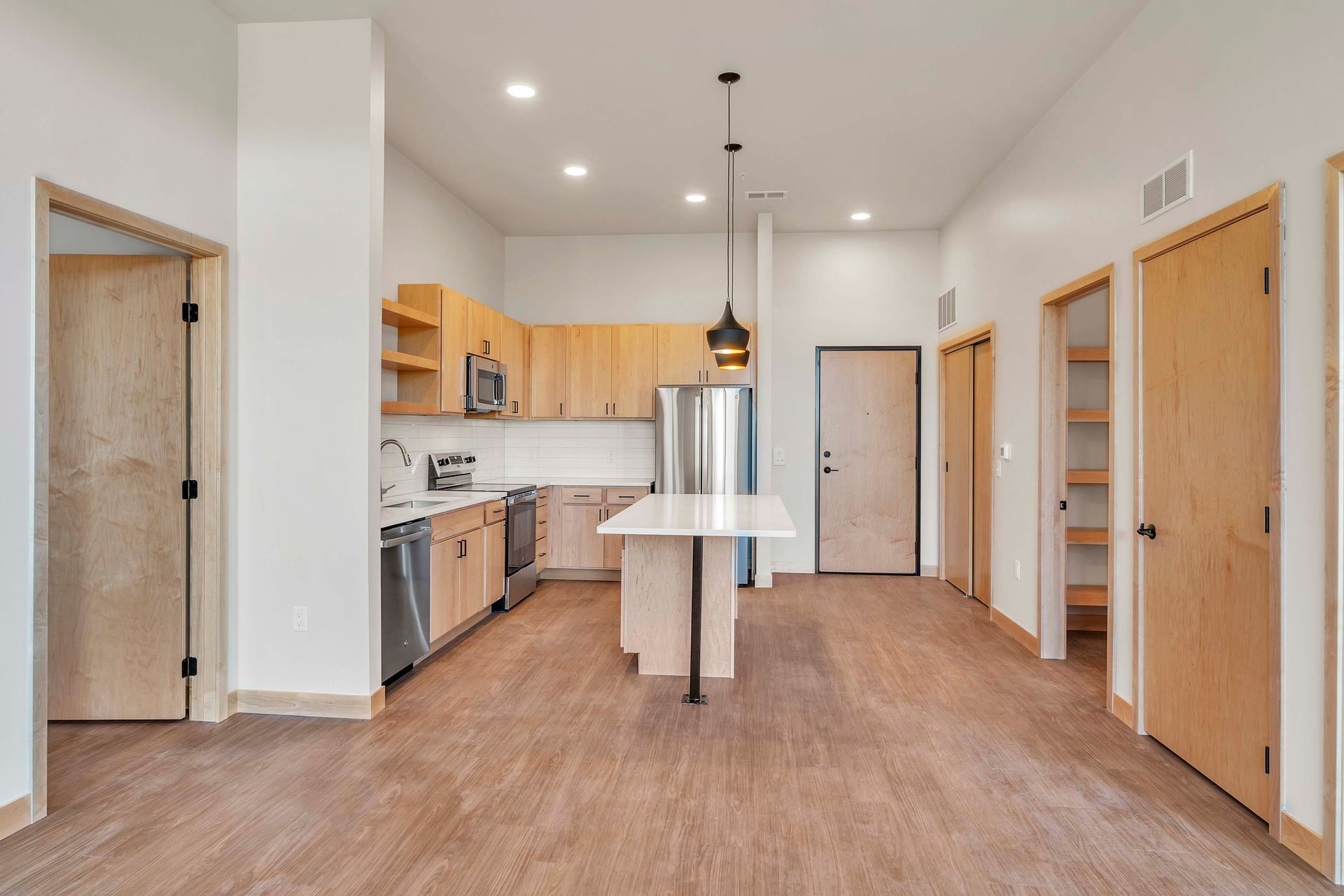 A kitchen with wooden cabinets , stainless steel appliances , and a large island.