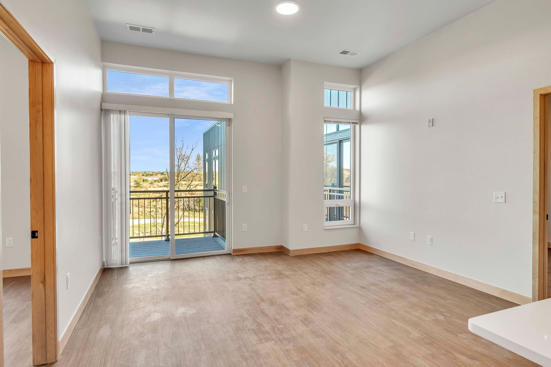 An empty living room with a balcony and sliding glass doors.