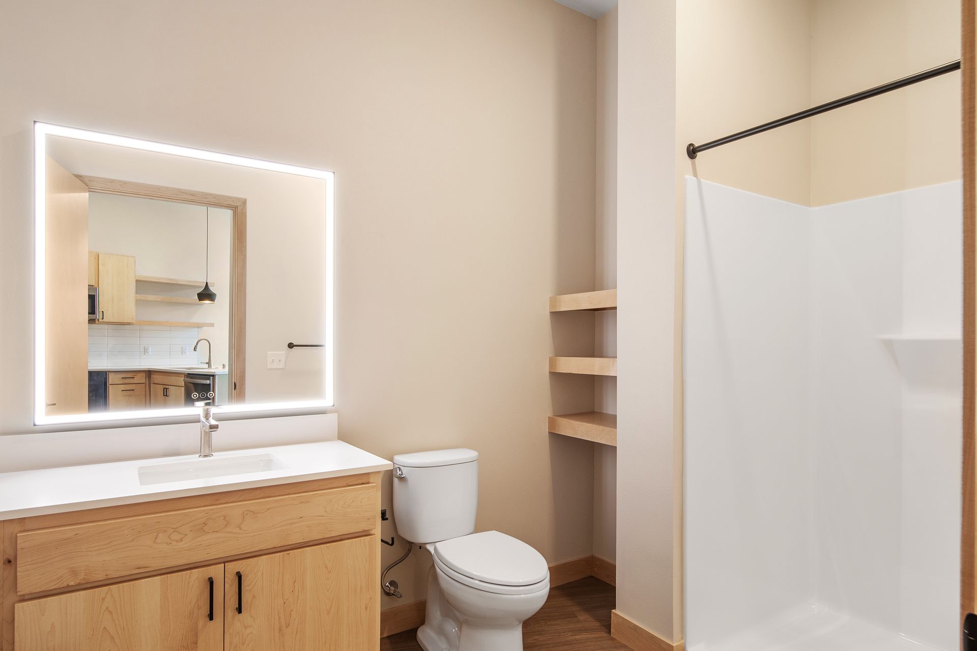 A bathroom with a toilet , sink , mirror and shower.