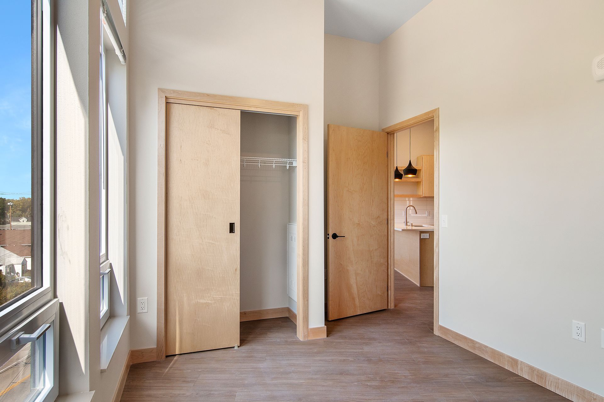 An empty bedroom with a closet and a window.