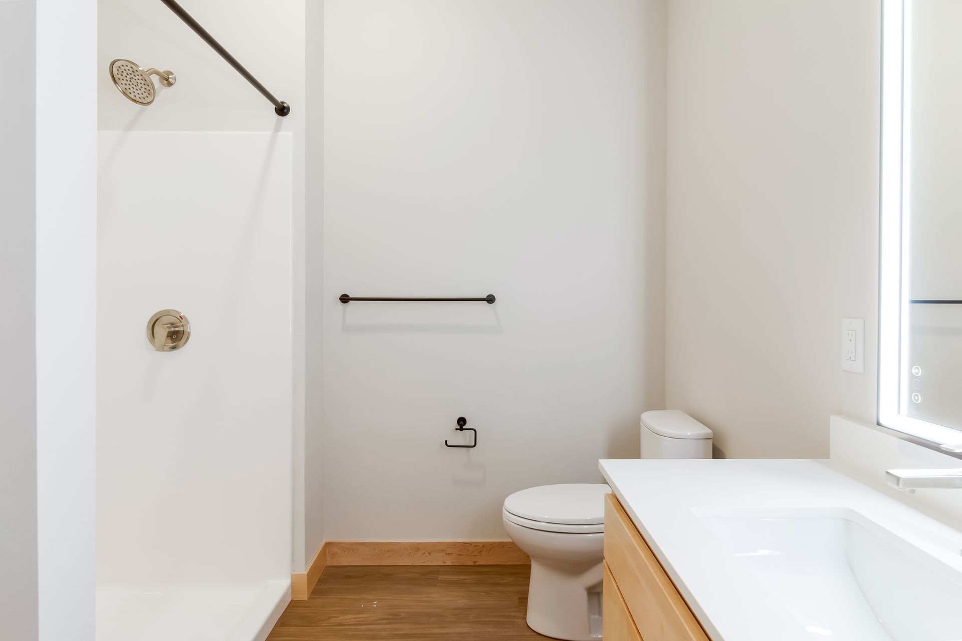 A bathroom with a toilet , sink , shower and mirror.