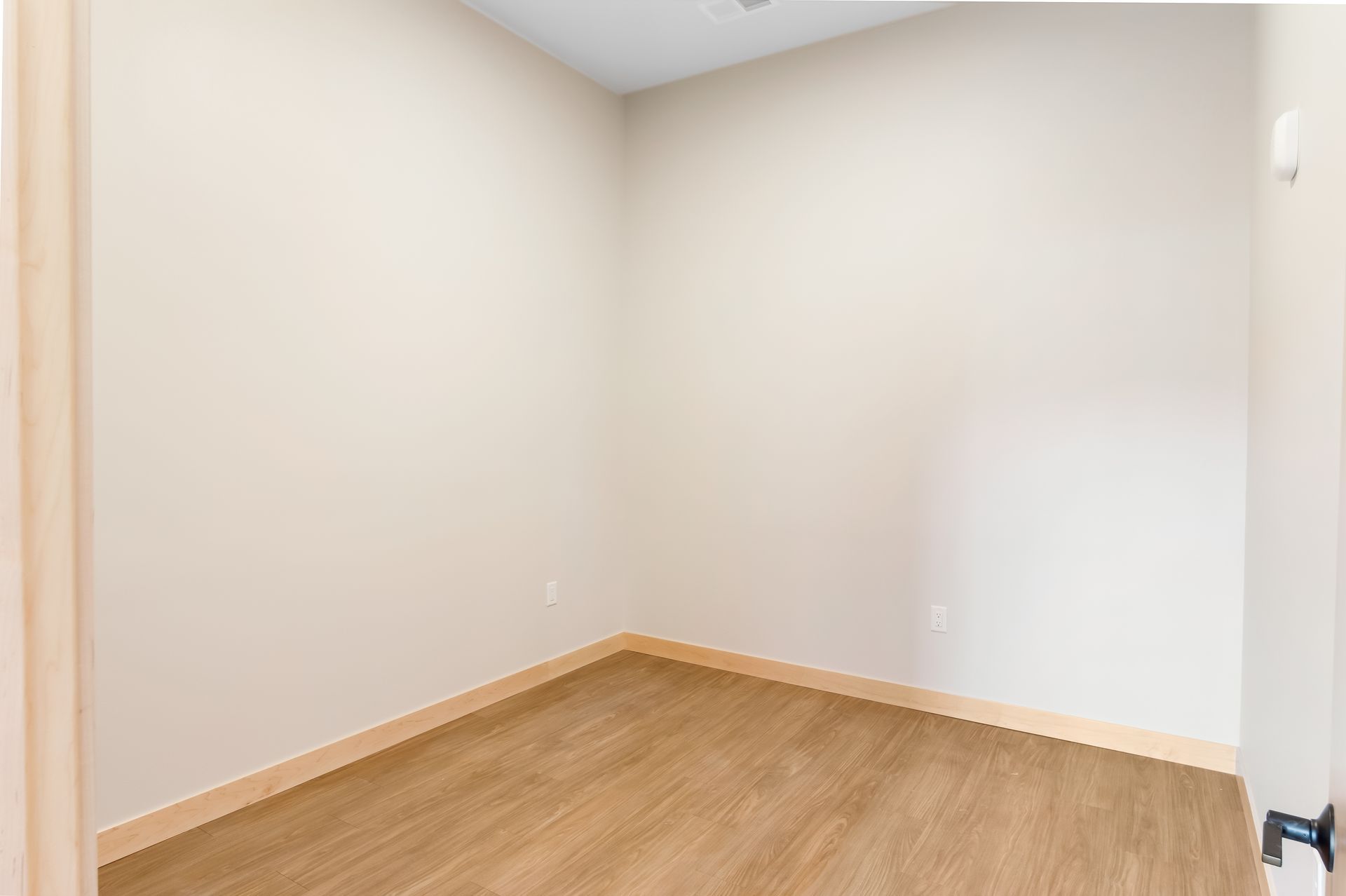 An empty room with wooden floors and white walls.