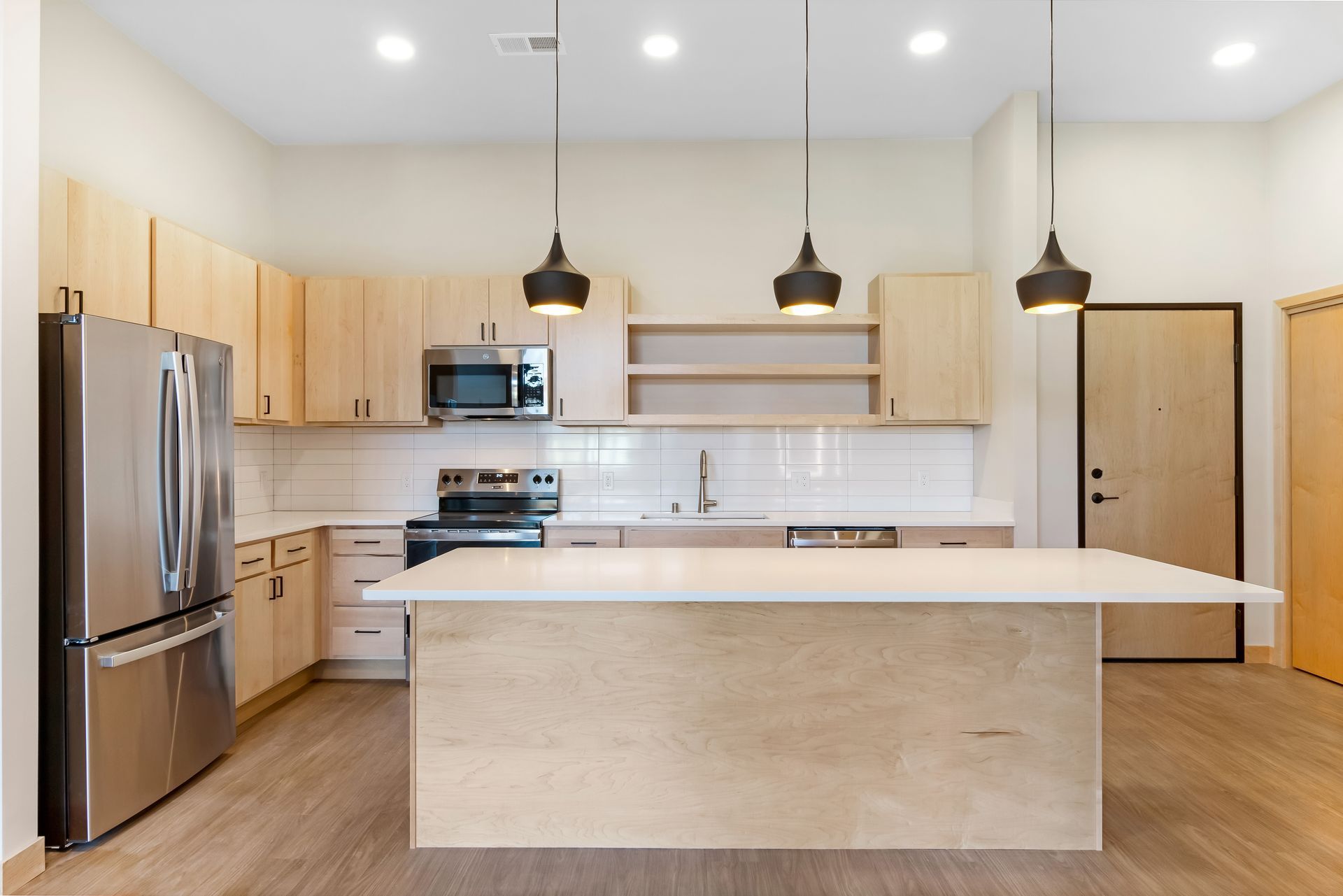 A kitchen with stainless steel appliances , wooden cabinets , and a large island.