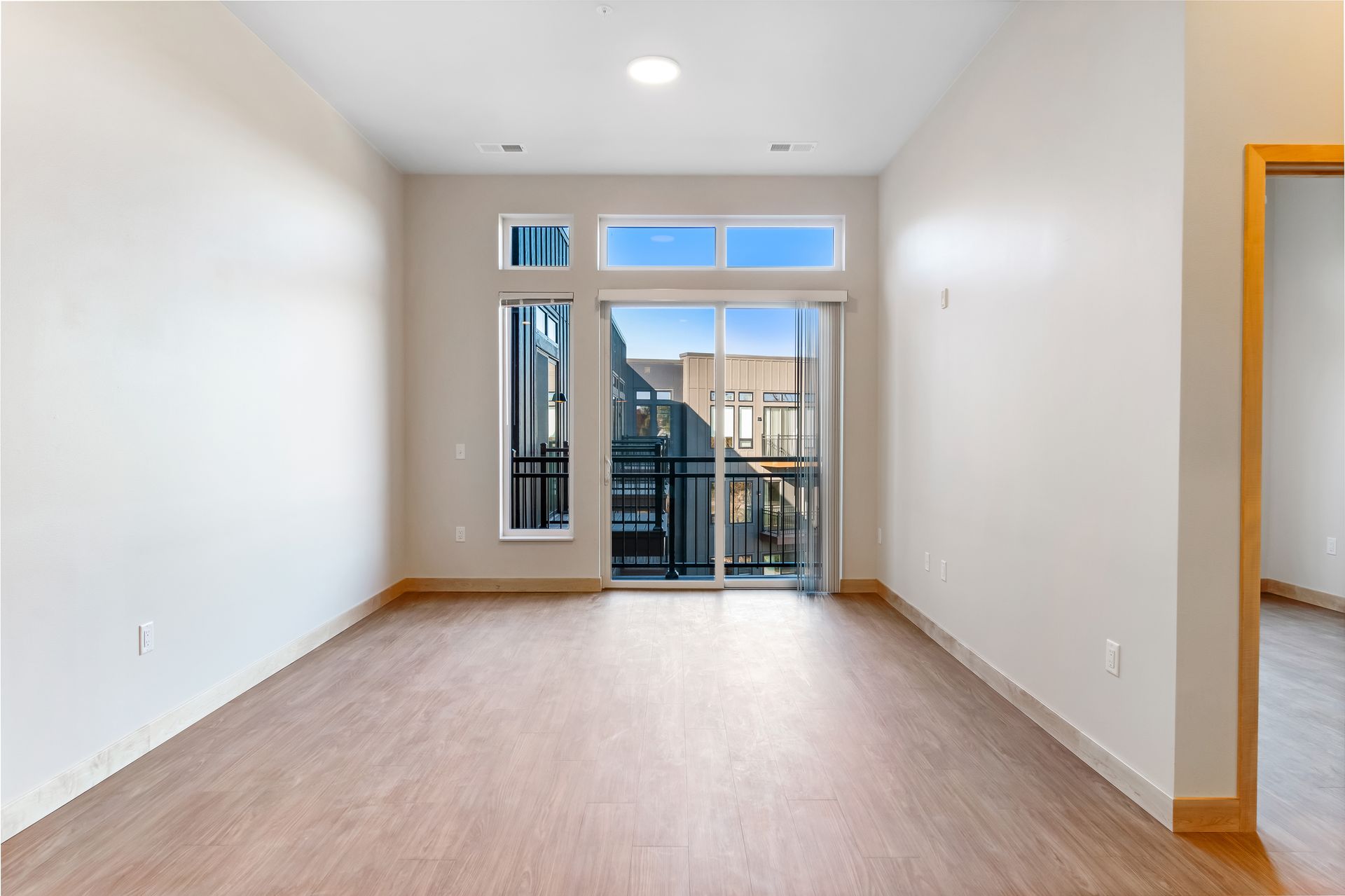 An empty living room with a balcony and sliding glass doors