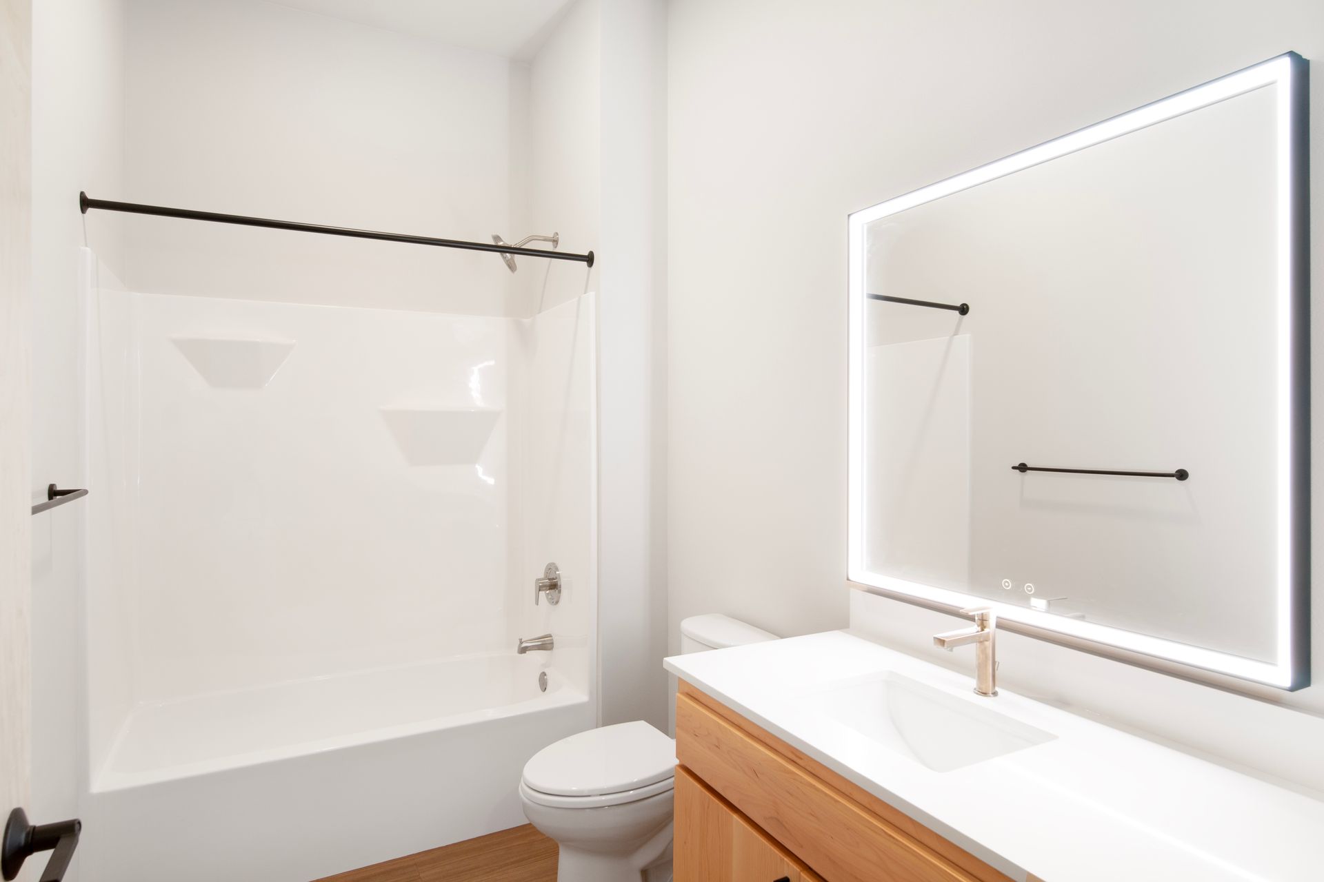 A bathroom with a toilet , sink , shower and mirror.