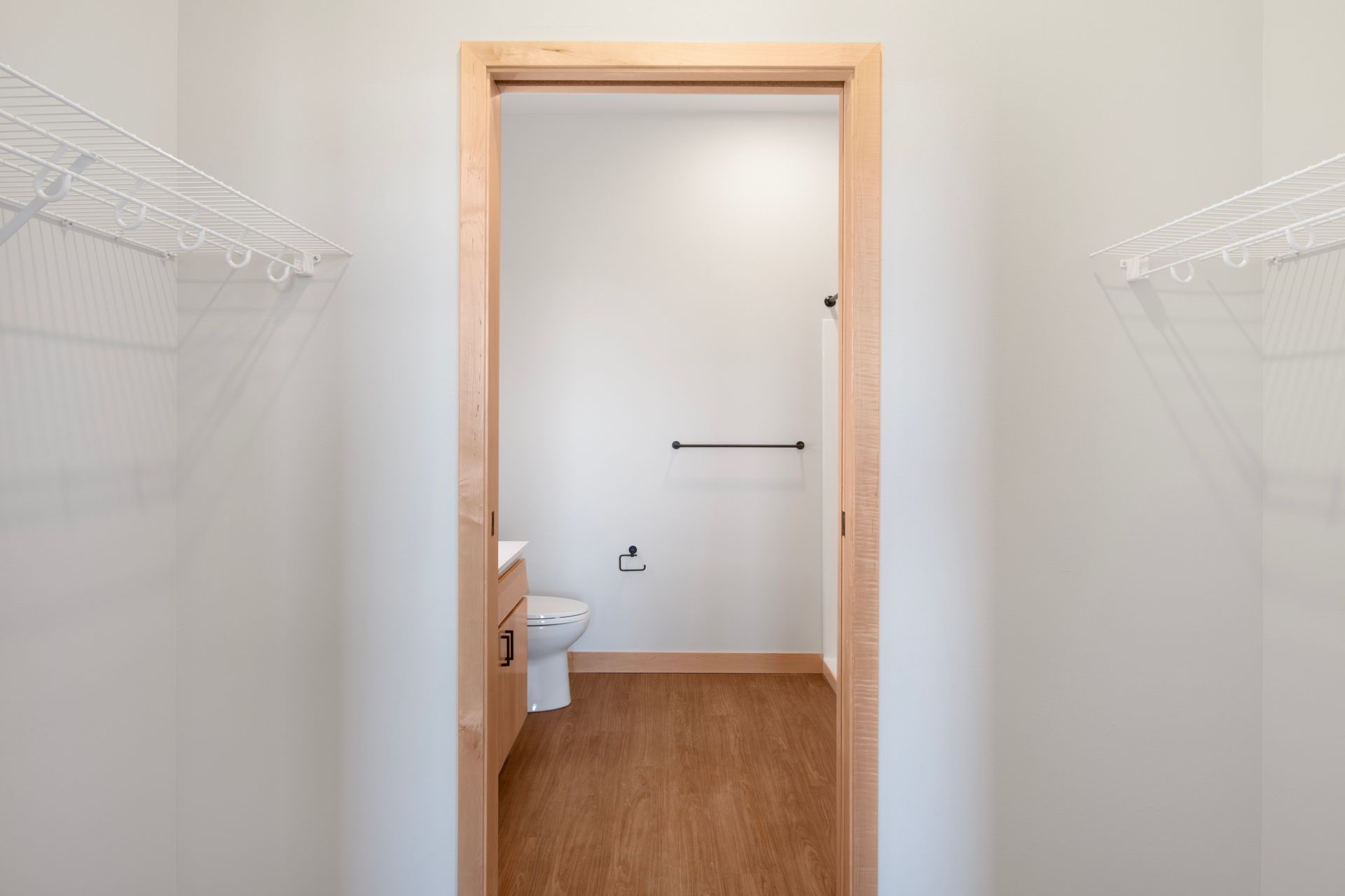 A walk in closet with a toilet , sink , and clothes racks.