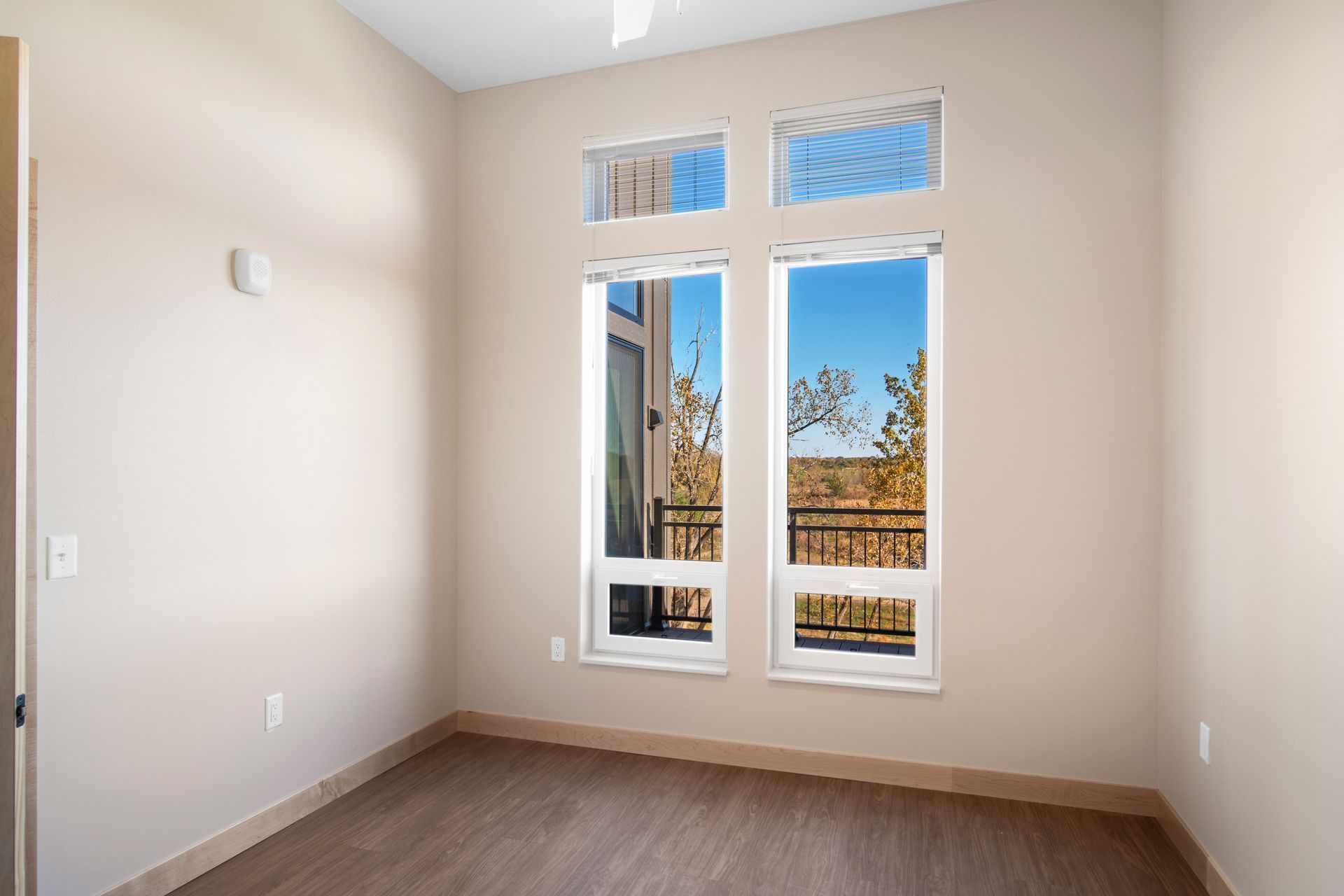 An empty room with two windows and a balcony.