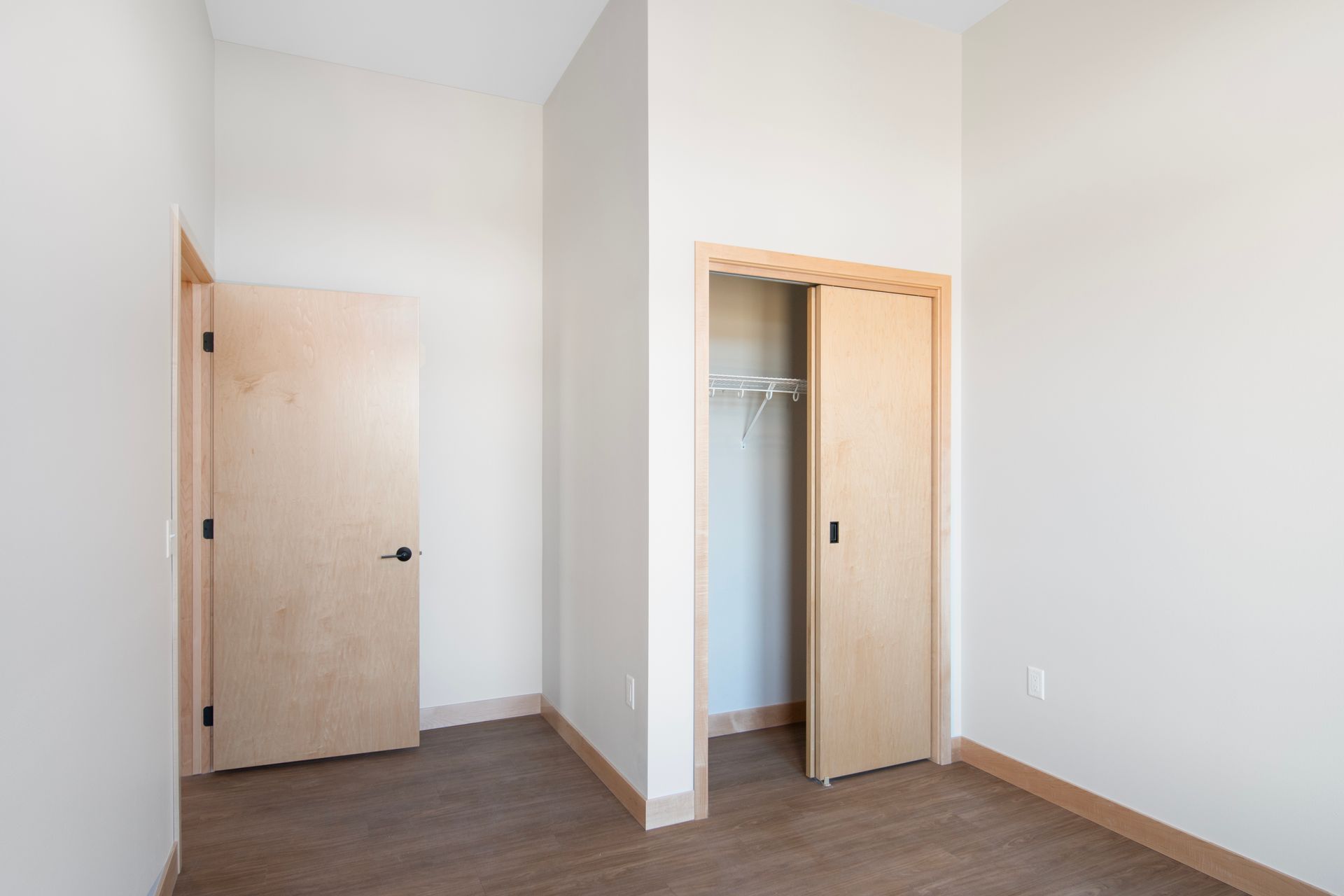 An empty bedroom with two doors and a closet.