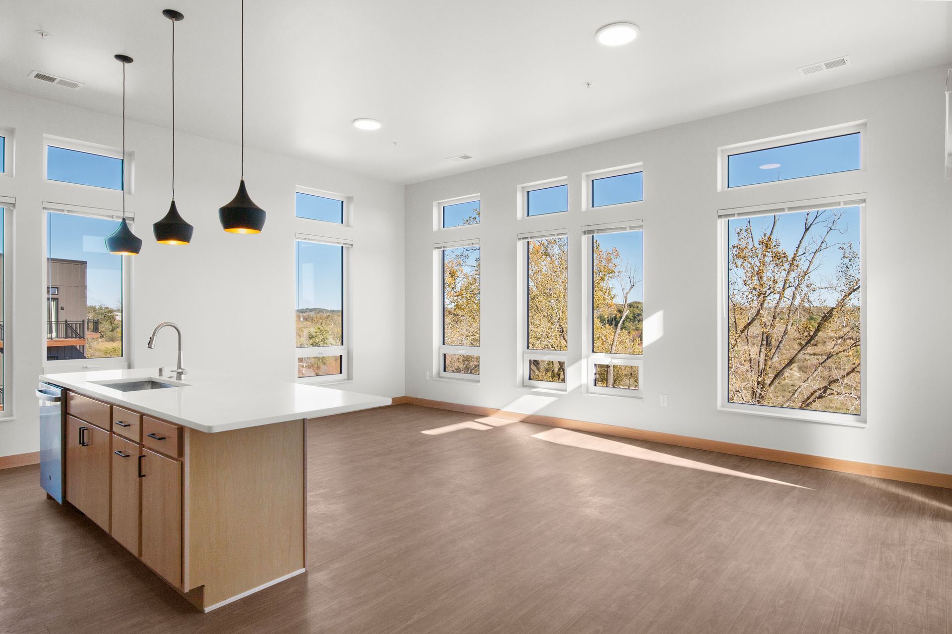 An empty kitchen with a large island and lots of windows.