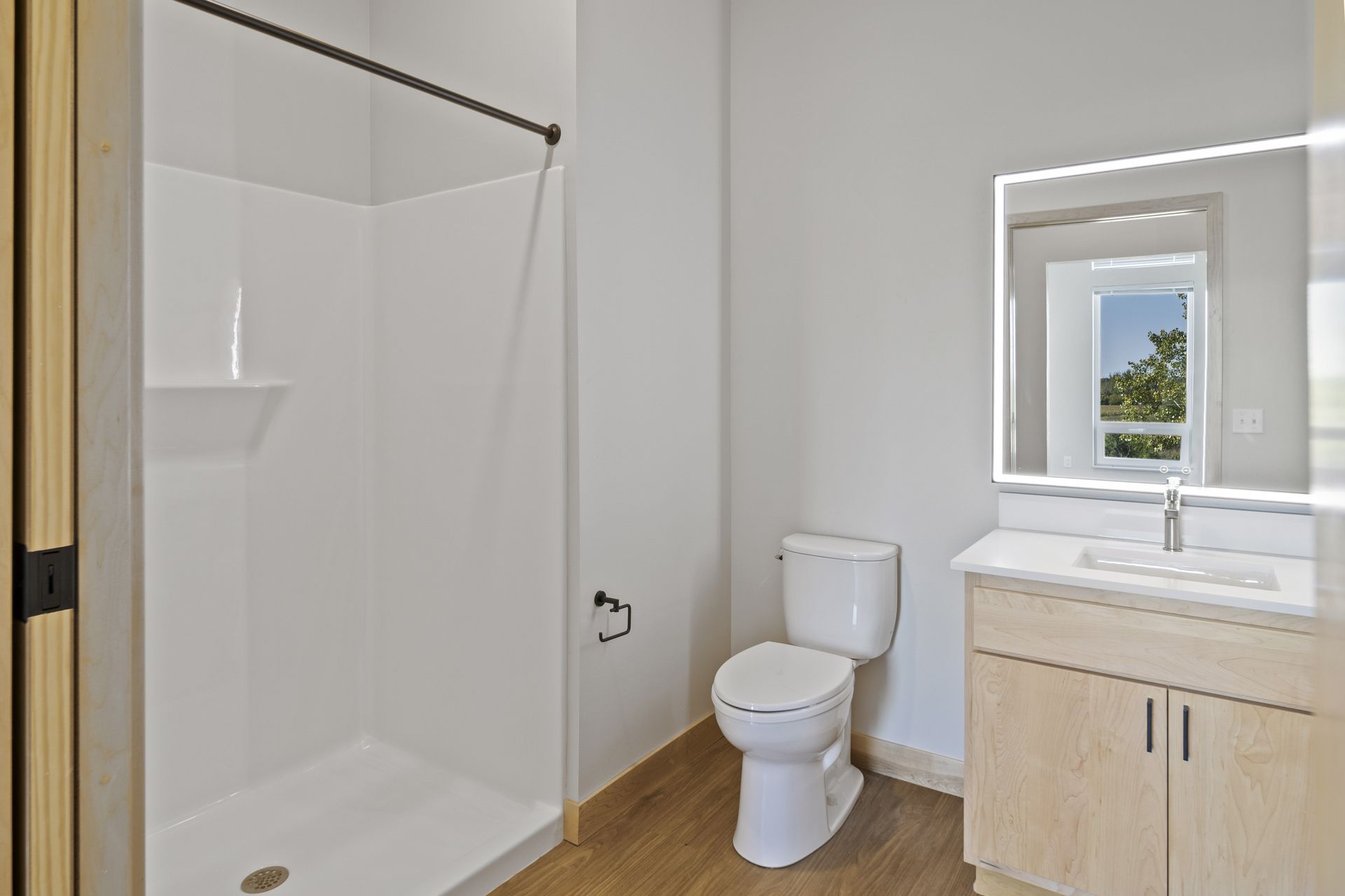 A bathroom with a toilet , sink , shower and led mirror.