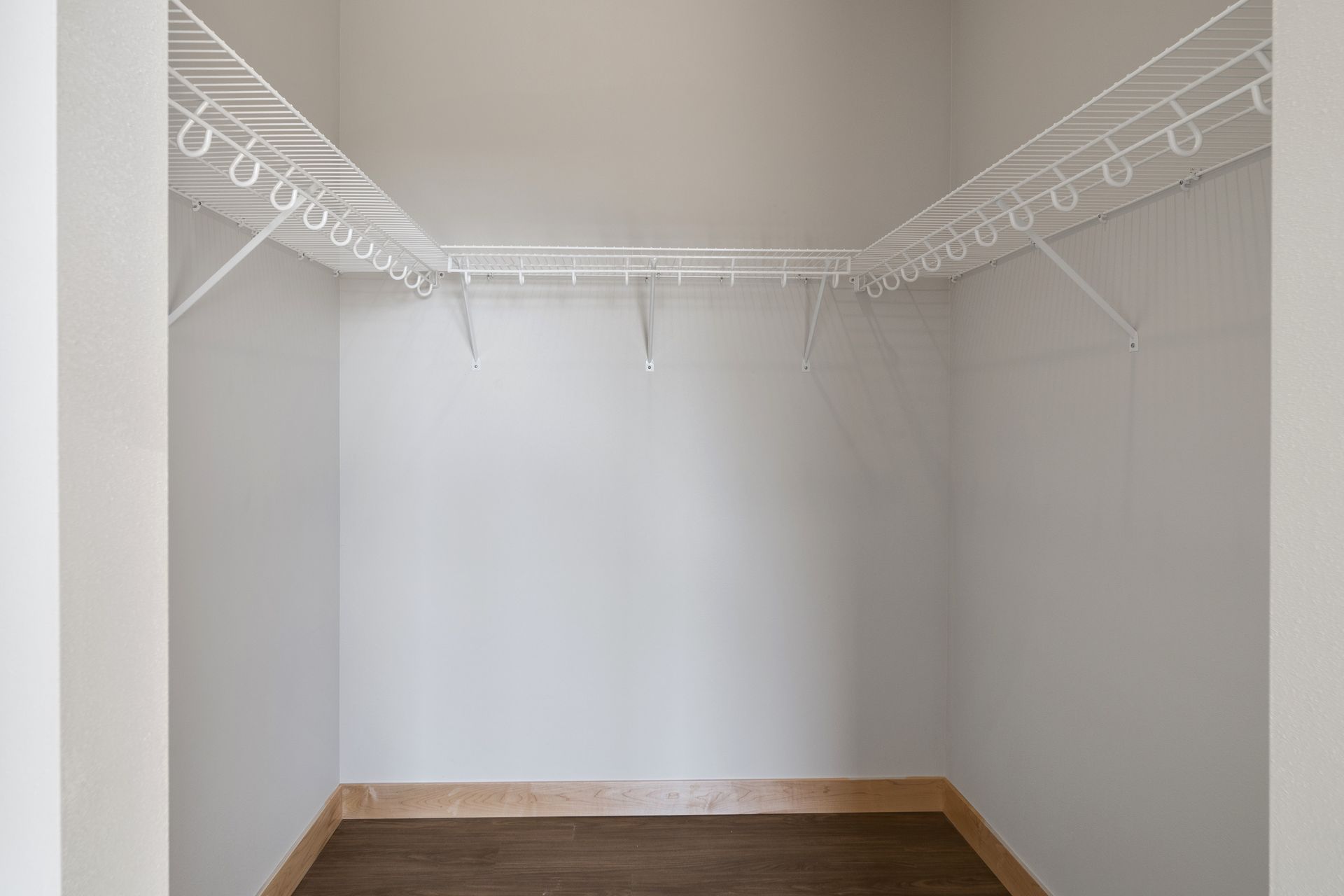 A large empty walk-in closet with white shelves and lvp floor.