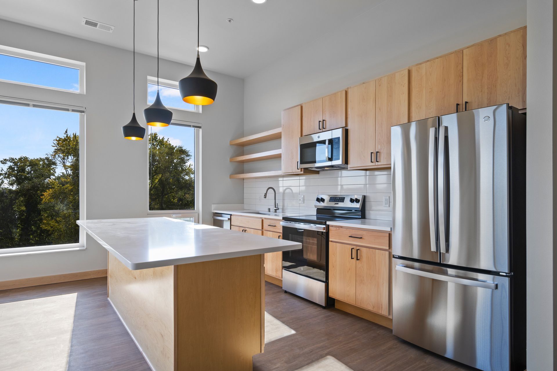 A kitchen with stainless steel appliances , wooden cabinets , and a large island.