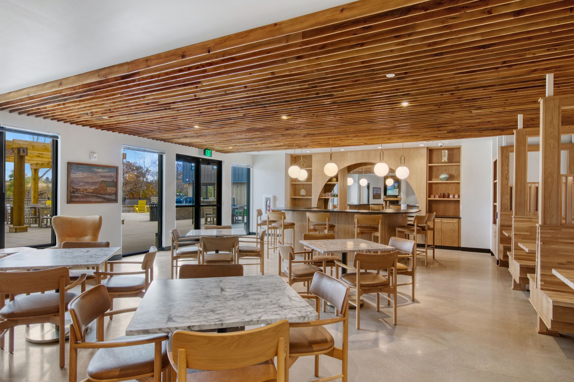 A large dining room with tables and chairs and a wooden ceiling.