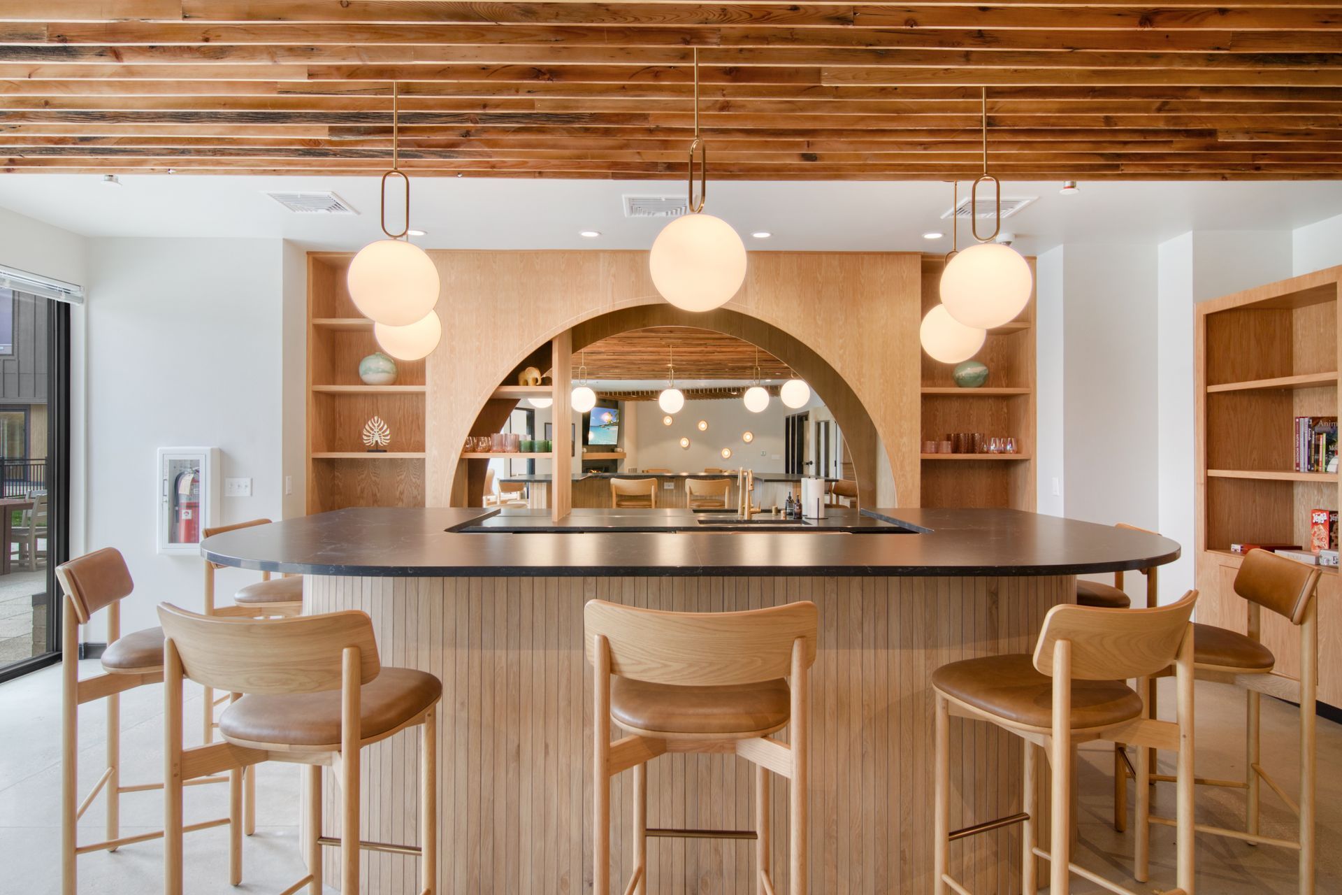 A kitchen with a bar and chairs and a wooden ceiling.