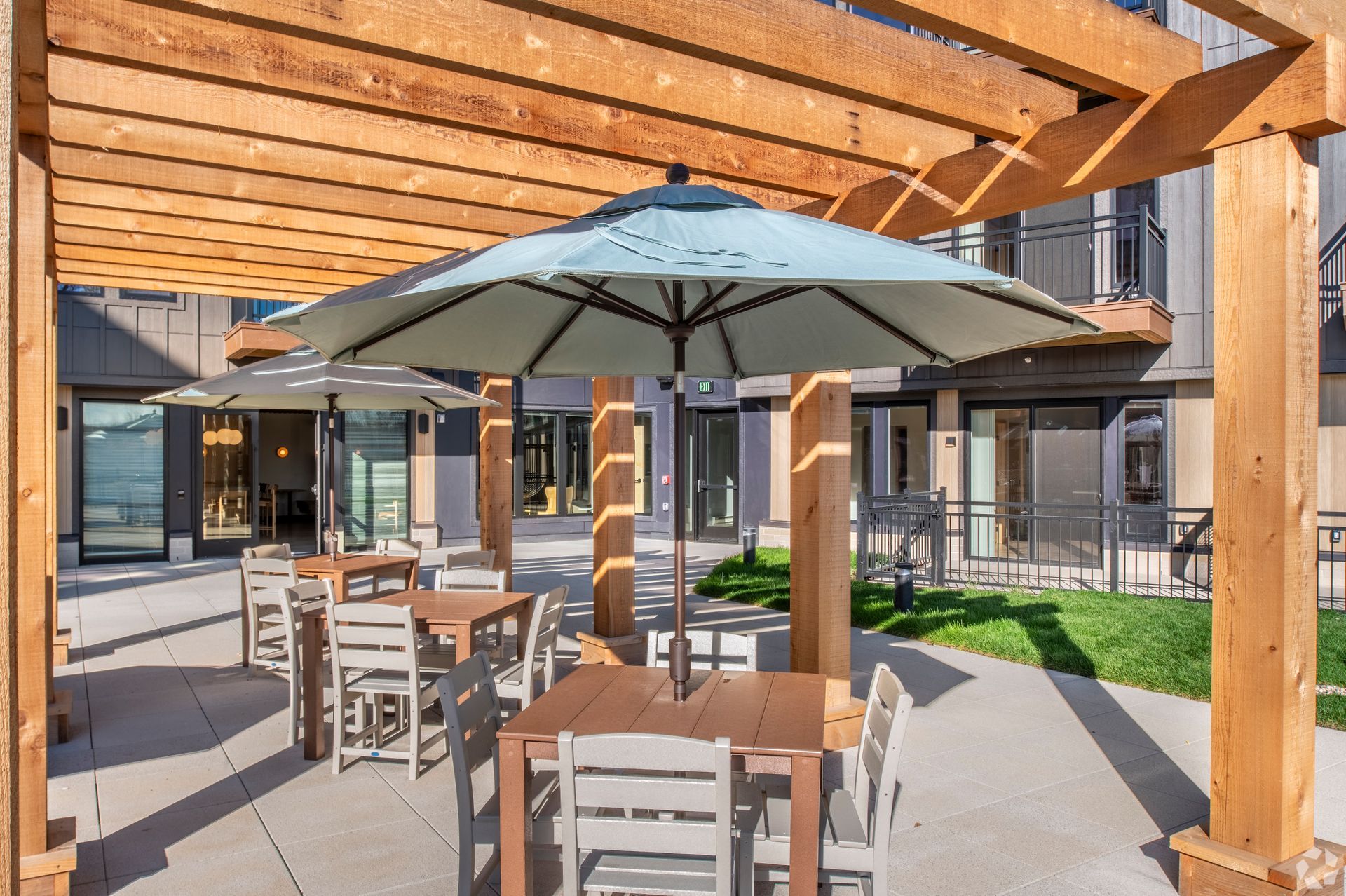 A patio with tables and chairs under a pergola with umbrellas.