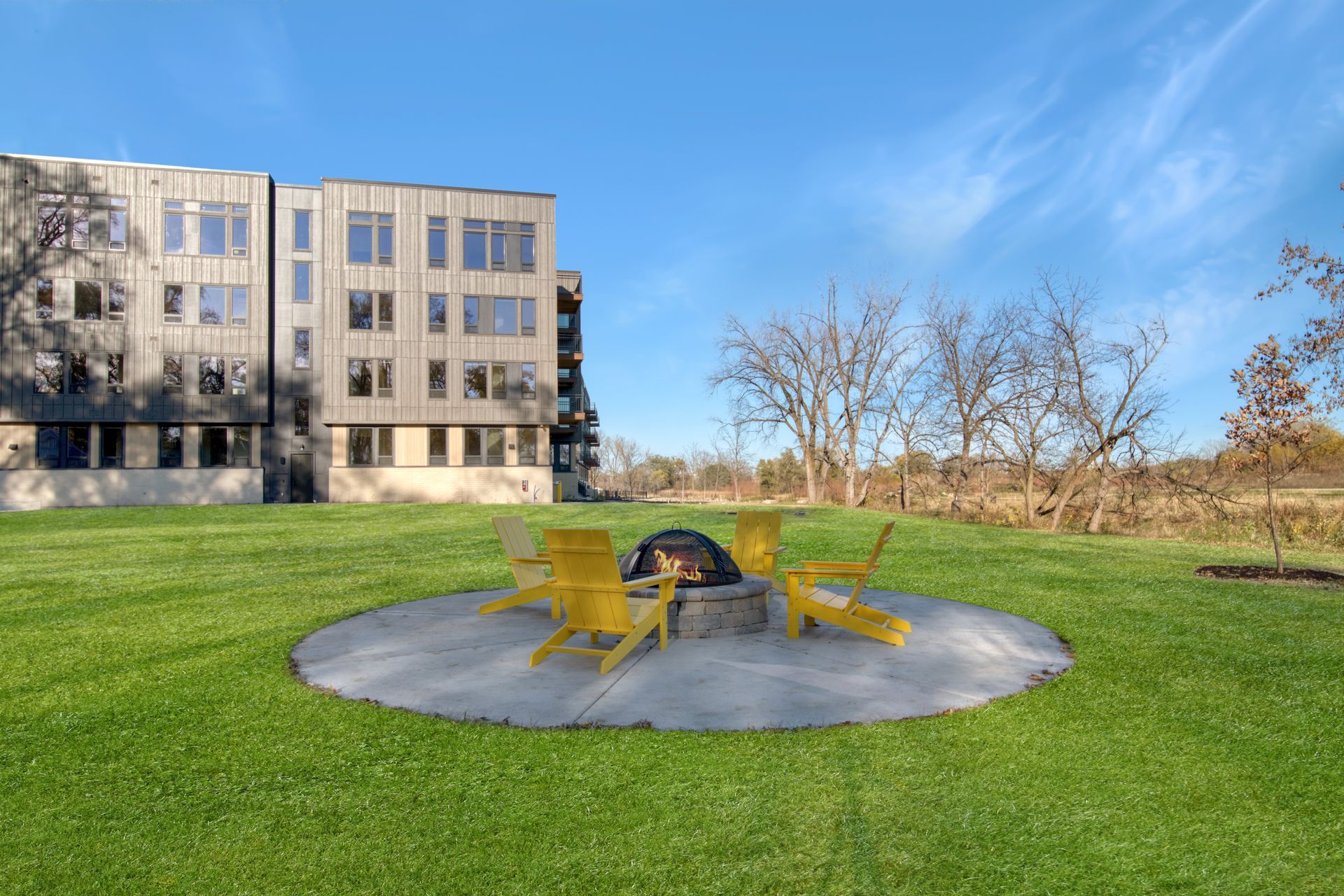 There is a fire pit in the middle of the grass in front of a building.