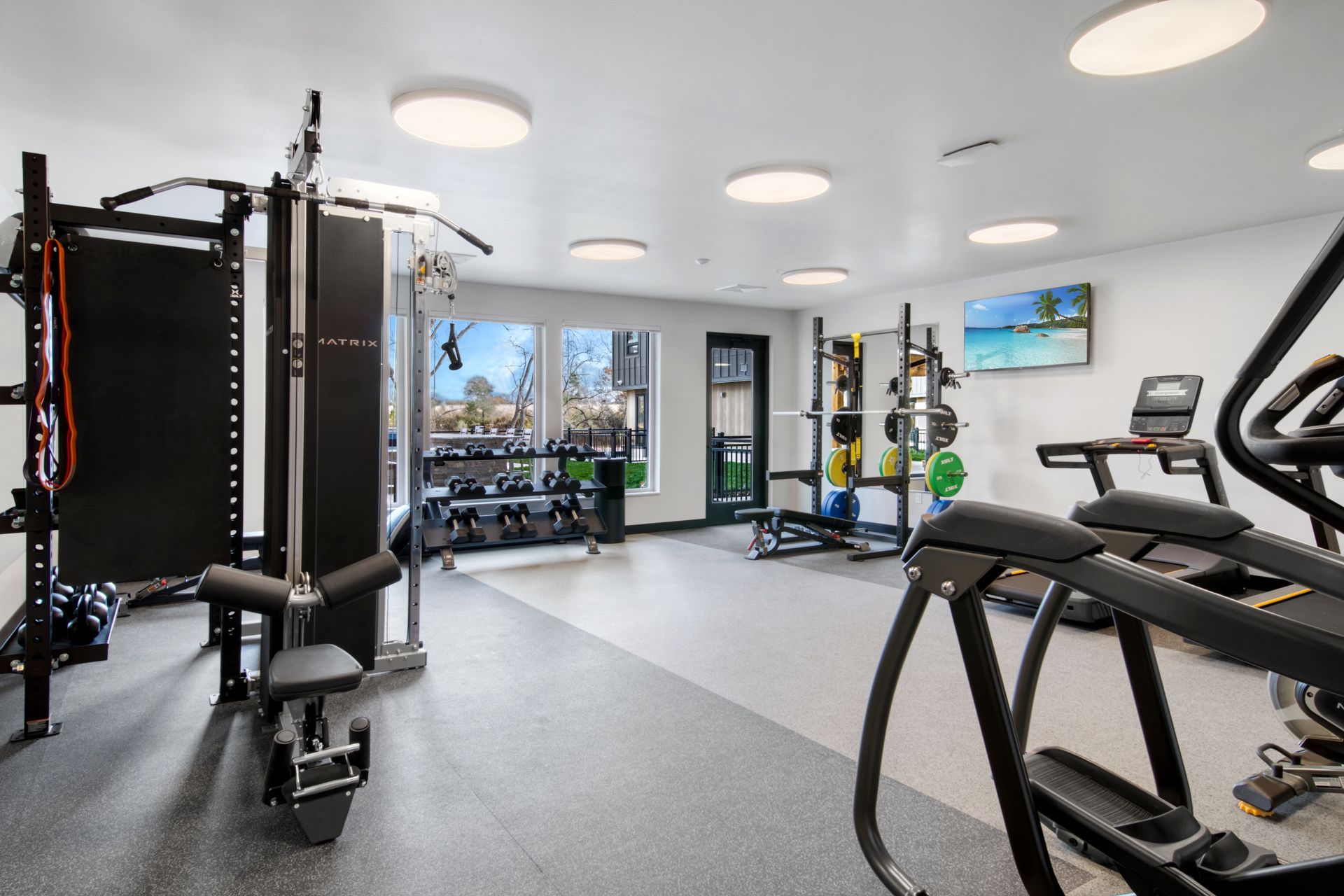 A large gym with a lot of equipment and a tv on the wall.